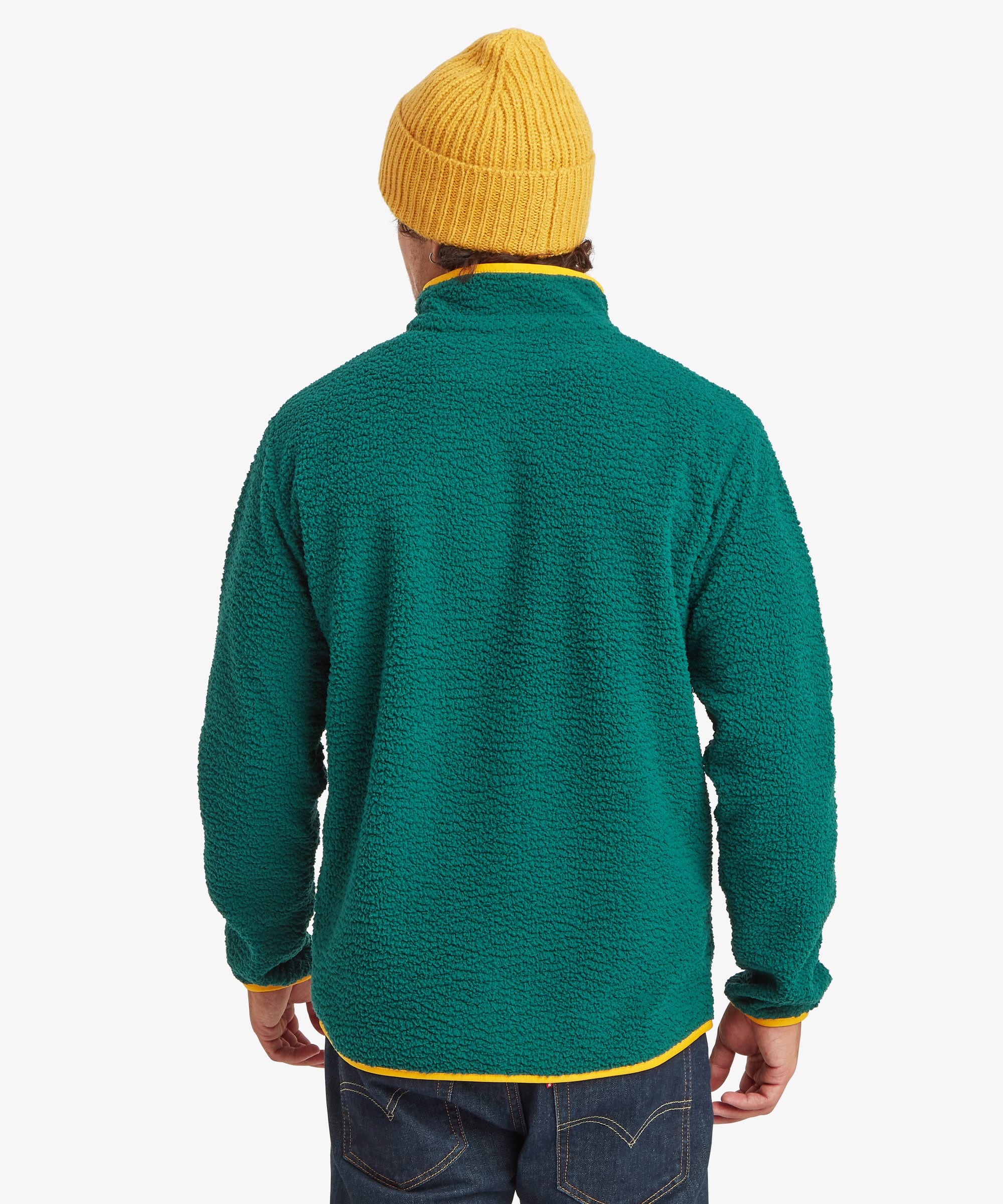 A man shown from the back wearing a textured green full zip fleece jacket with yellow trim, a yellow knit beanie, and dark blue jeans against a light gray background.