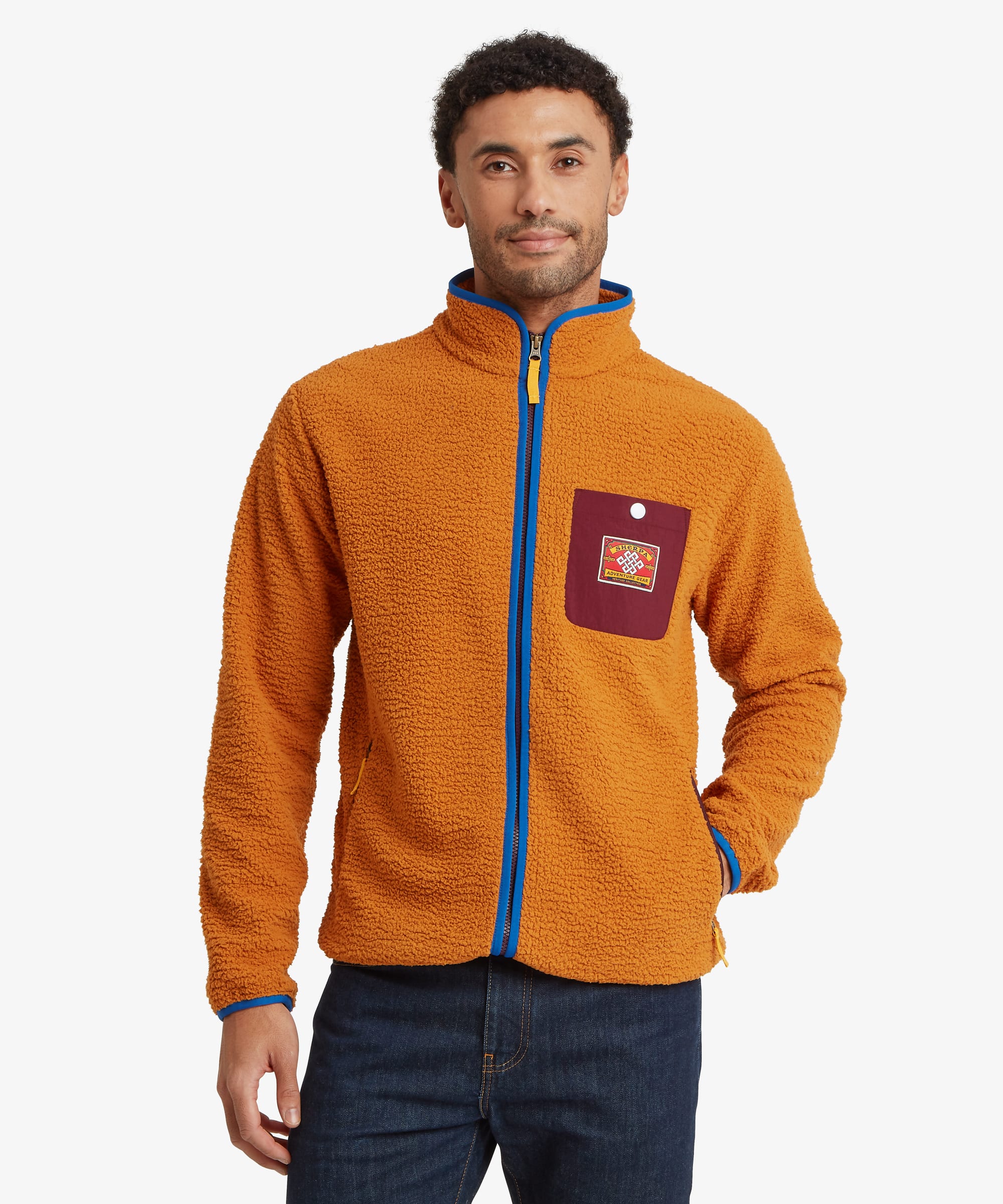 Front view of an orange sherpa fleece jacket featuring a full-length blue contrast zipper, stand collar, zip hand pockets, and a contrast chest patch pocket with logo patch.