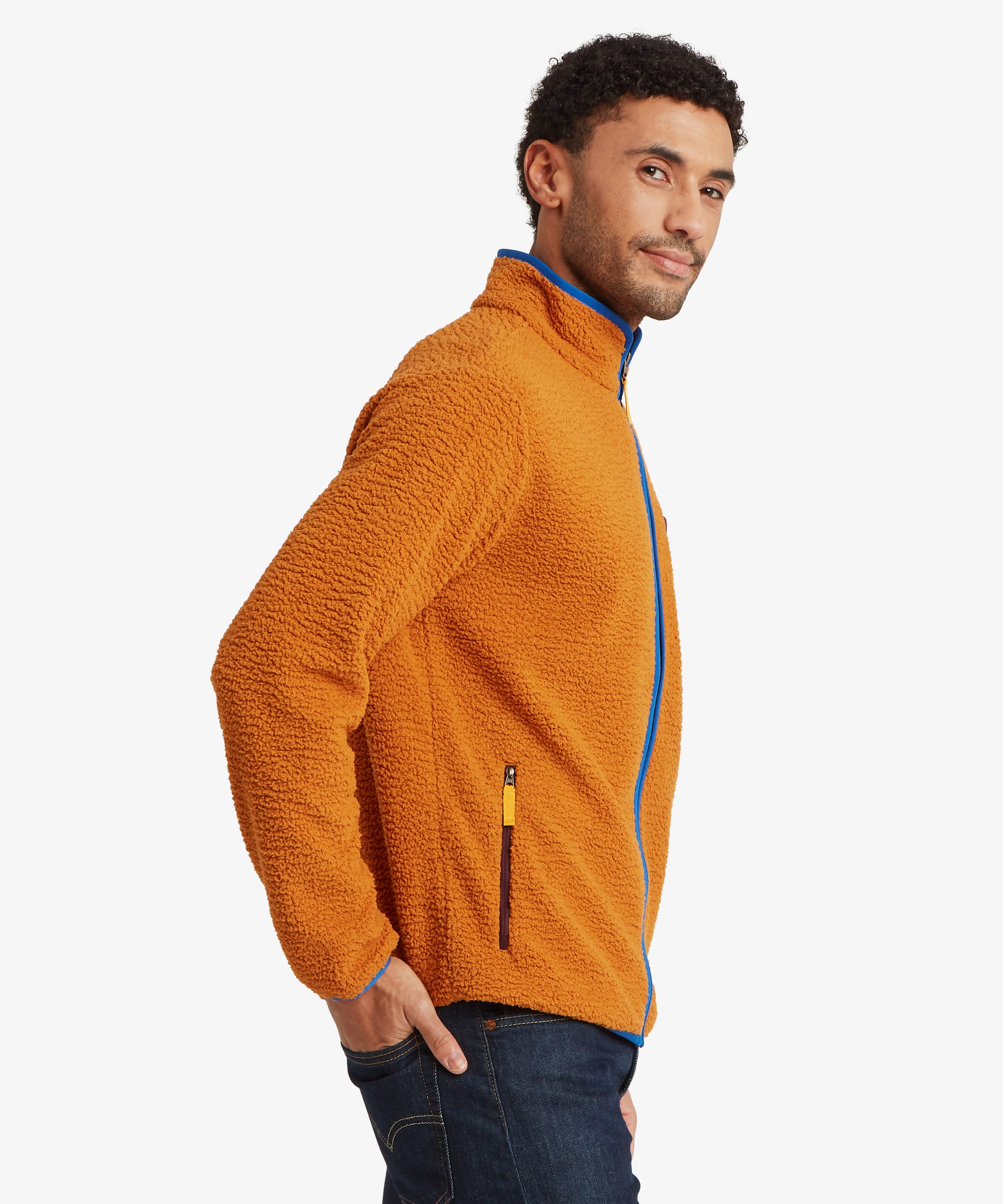 Side profile of an orange sherpa fleece jacket showing the raised collar, full zip closure, side zip pocket, and textured fleece fabric.