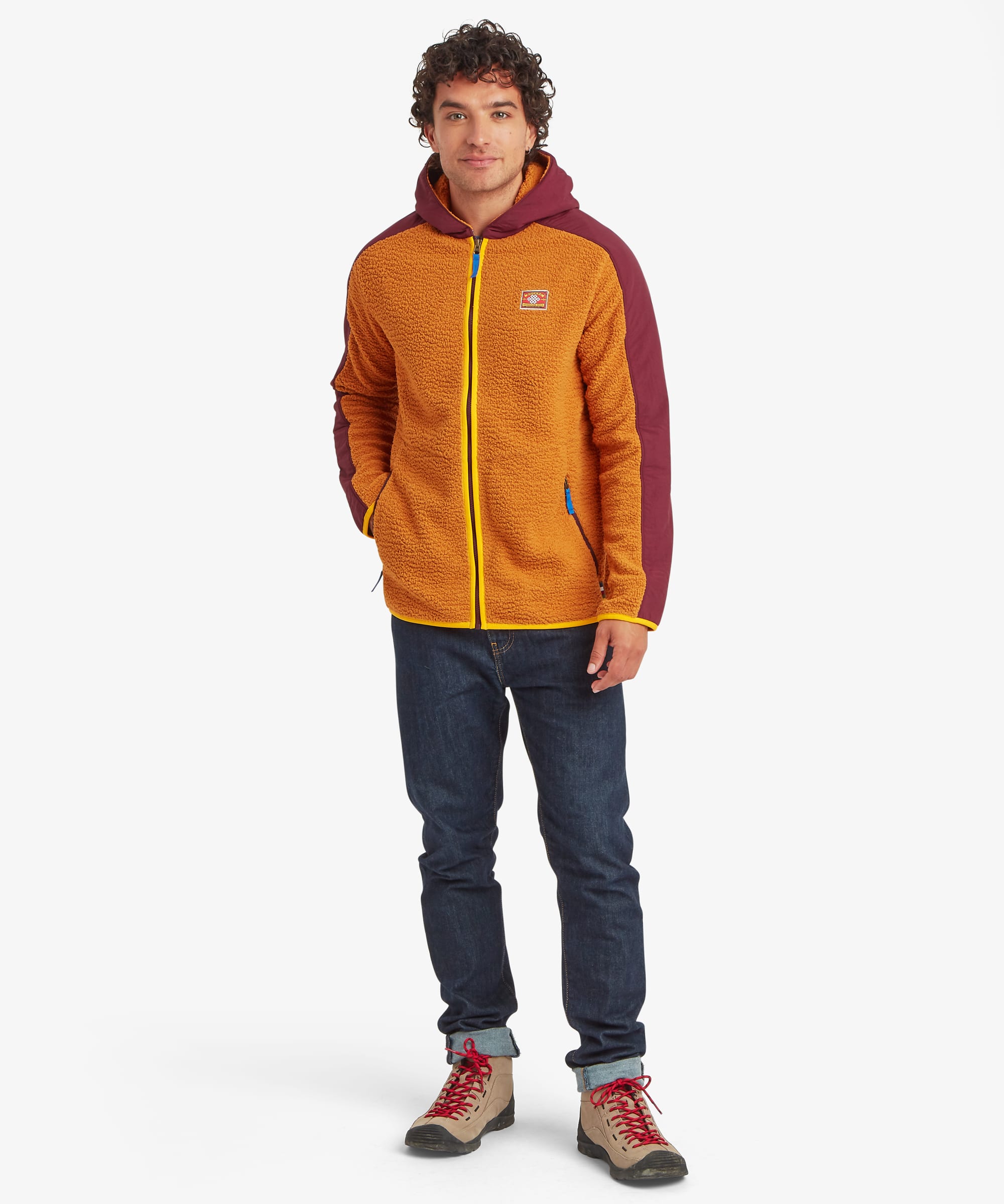 Full-length front view of a male model wearing the yellow Sherpa Tarcho Hooded Jacket, showing the relaxed fit, contrasting hood and sleeves, contrasting binding, full-zip front and zipped pockets with blue zip pullers.