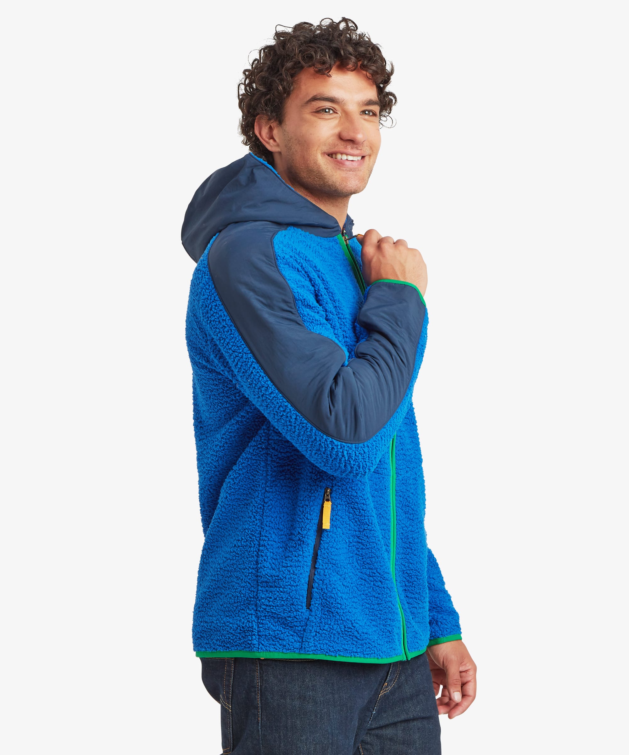Male model wearing the blue Sherpa Tarcho Hooded Jacket from a three-quarter side angle, highlighting the soft fleece fabric, contrasting hood and sleeves, and full-zip front.
