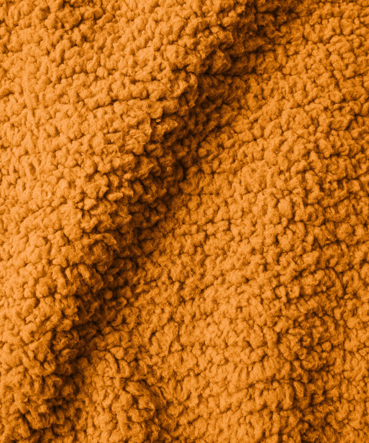A close-up of a textured fabric in a  orange color, showing the plush texture.