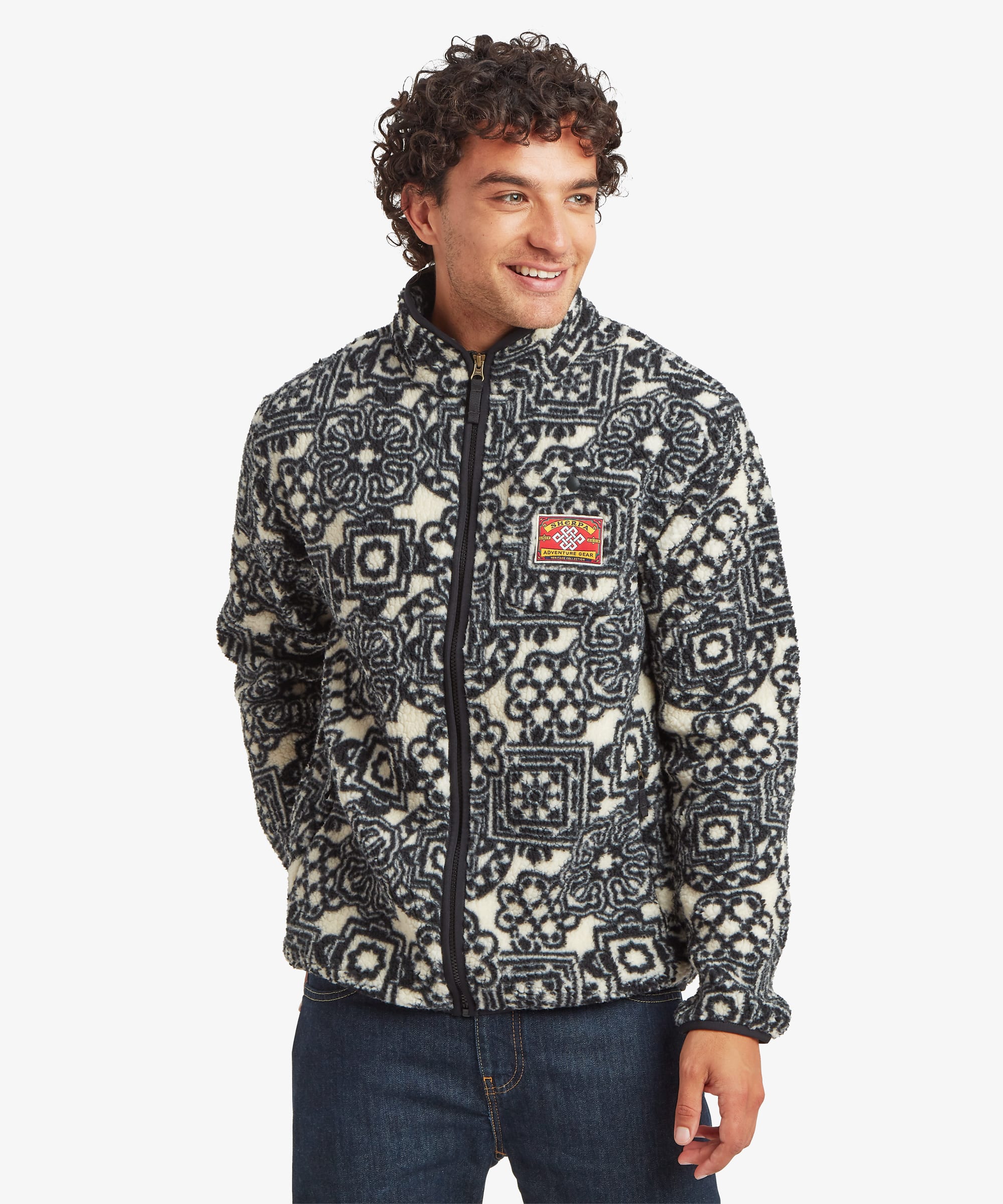 Front view of a black printed full-zip fleece jacket featuring an allover geometric pattern and contrast chest patch. Designed with a stand collar, zip-front closure, and relaxed fit.