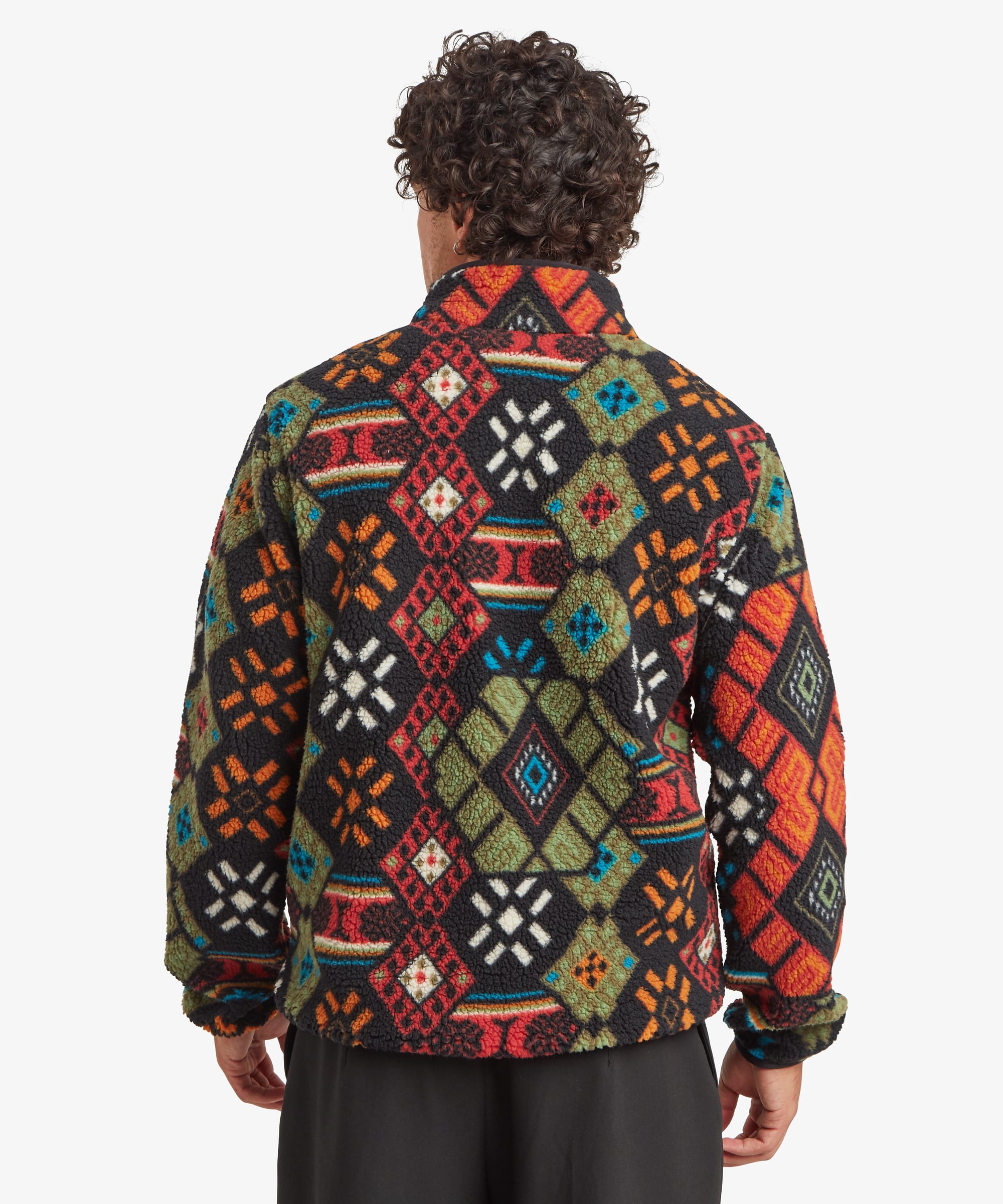 Rear view of a male model wearing the Sherpa Tarcho Printed Full Zip Jacket in black, showing the bold multicoloured geometric pattern across the back, long sleeves, stand collar and relaxed fit.
