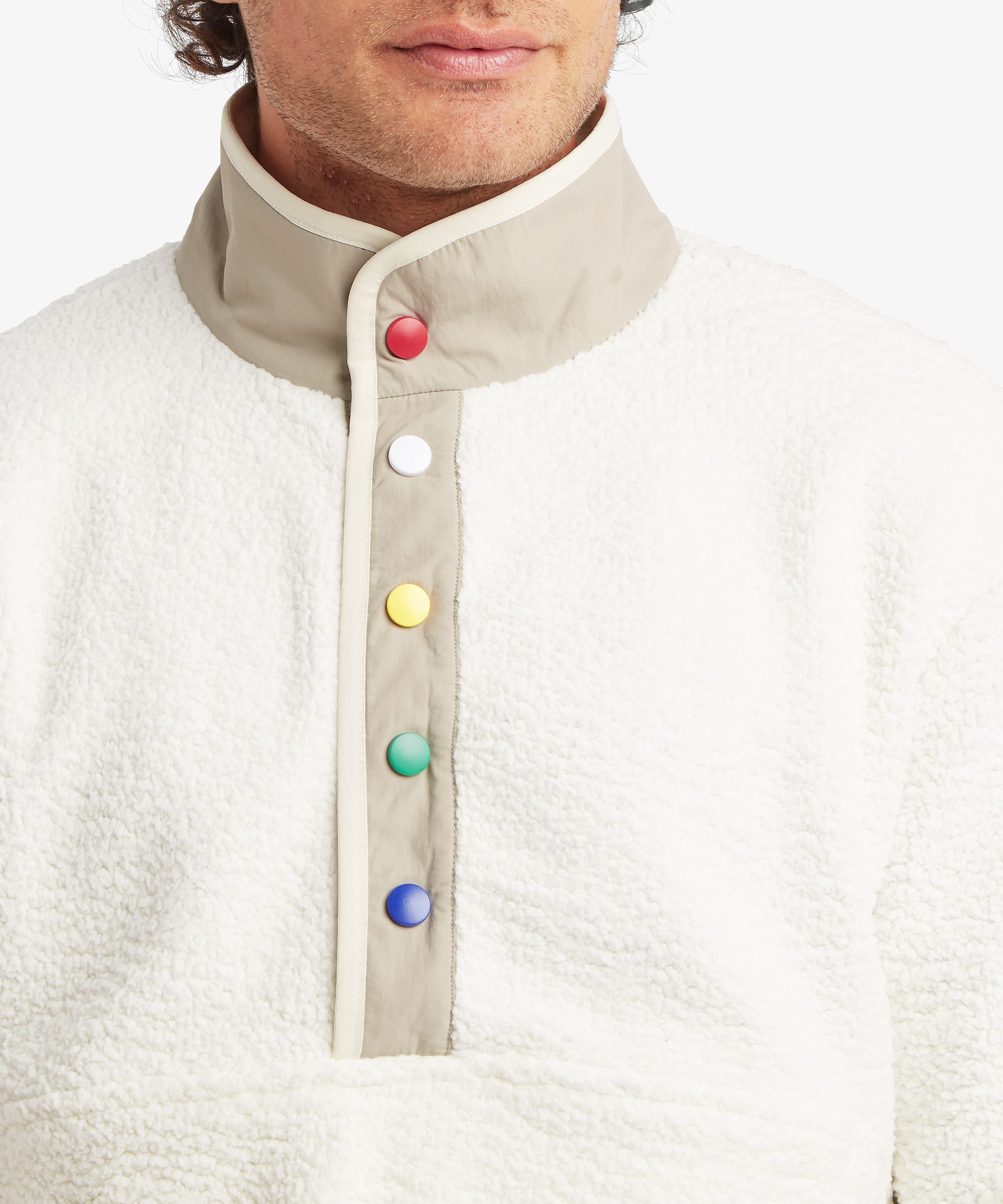 Close-up of a male model wearing the Sherpa Tarcho Snap Pullover in white, highlighting the textured fleece fabric, stand collar, contrast facing and colourful snap-button placket.