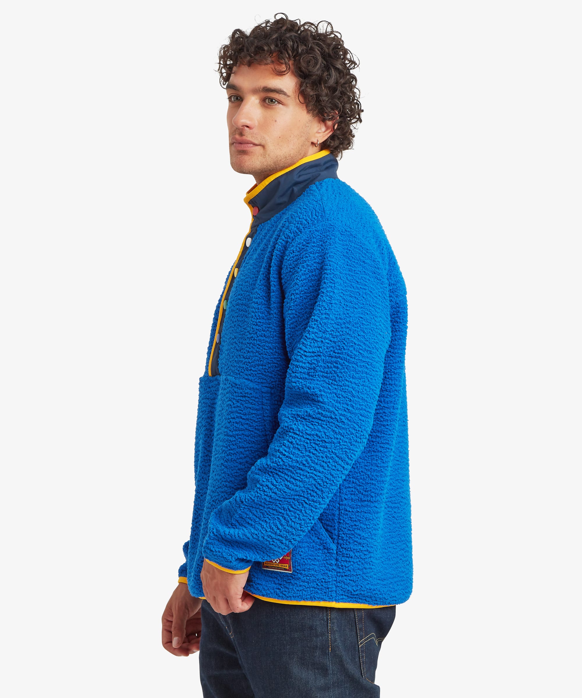 Side profile of a male model wearing the Sherpa Tarcho Snap Pullover in blue, highlighting the relaxed fit, high stand collar, long sleeves and textured fleece construction.