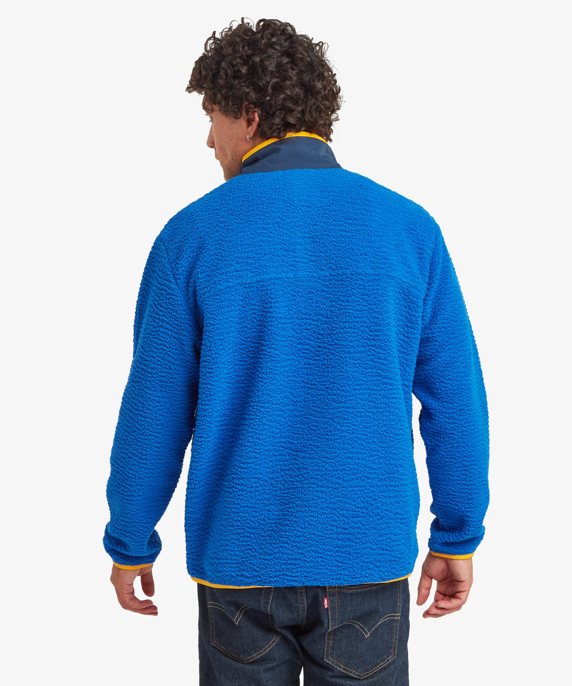 Rear view of a male model wearing the Sherpa Tarcho Snap Pullover in blue, showing the clean back design, stand collar, relaxed fit and long sleeves.