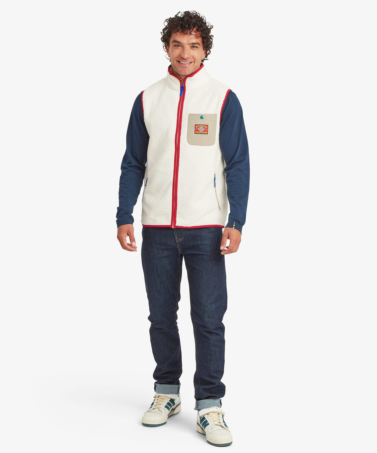 Front view of a smiling male model wearing the Sherpa Tarcho Vest in white textured fleece.