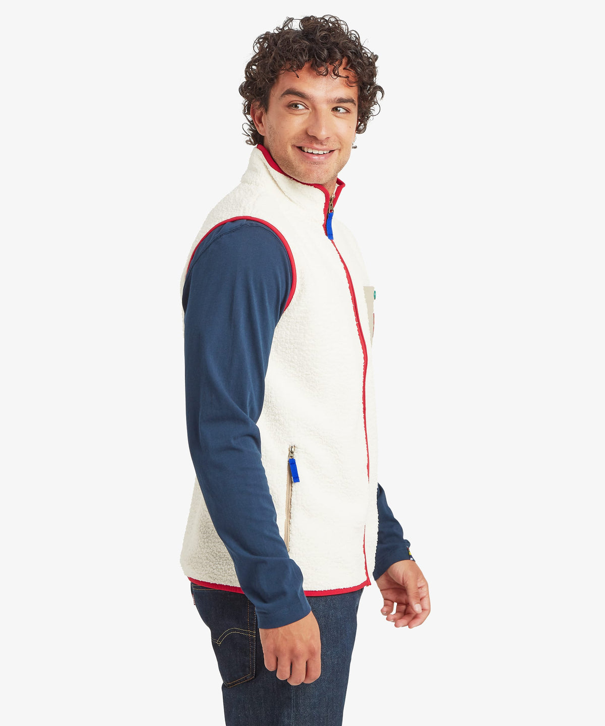 Side profile of a male model wearing the Sherpa Tarcho Vest in white fleece with red trim.