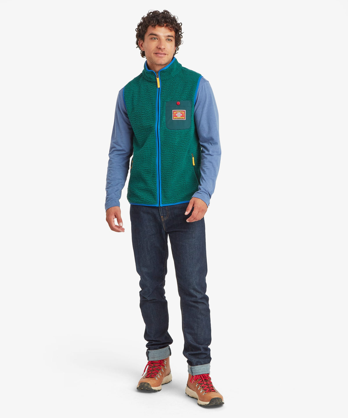 A man modeling a green fleece vest with dark blue jeans.