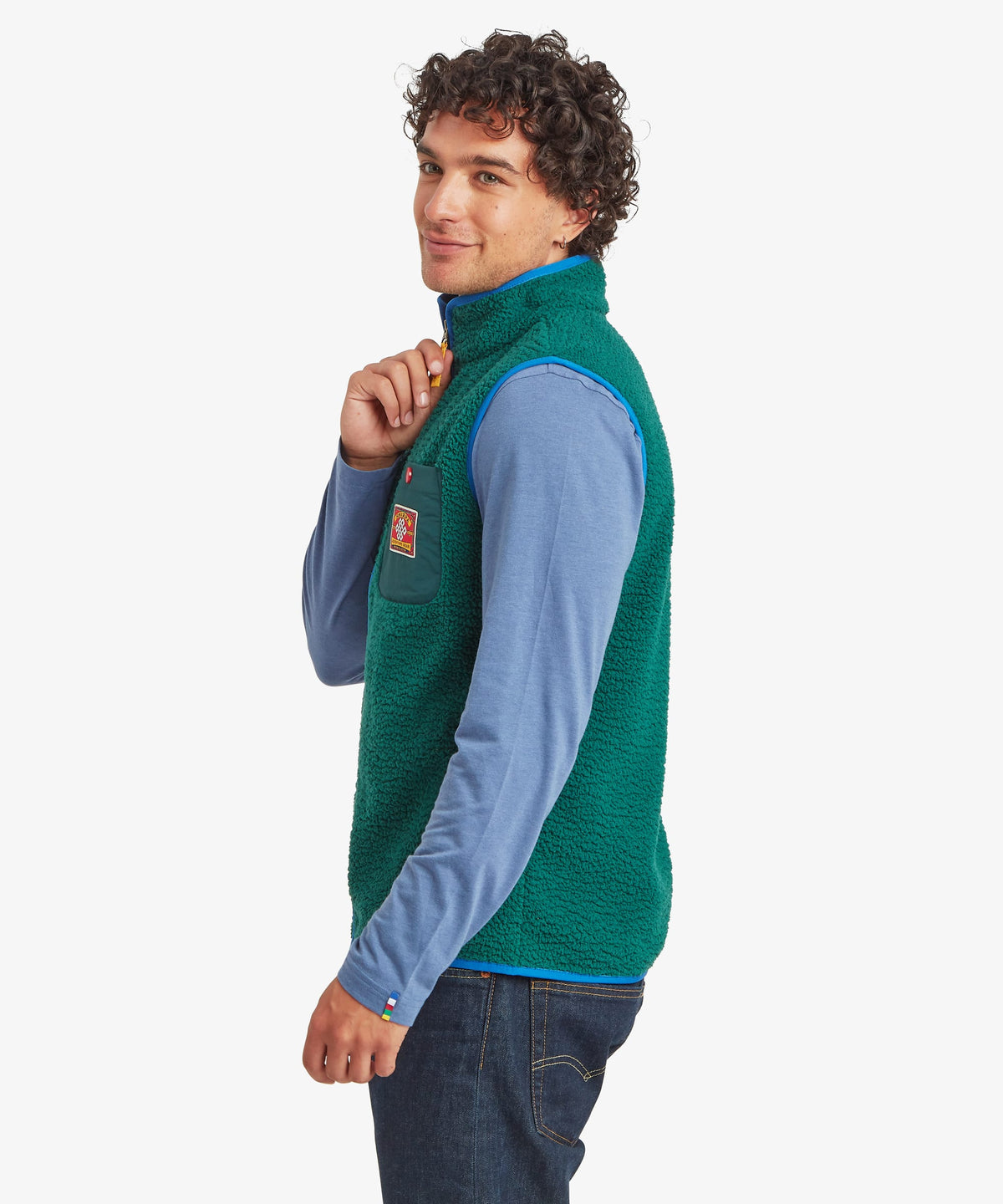 A man wearing a green fleece vest over a light blue long-sleeve shirt.