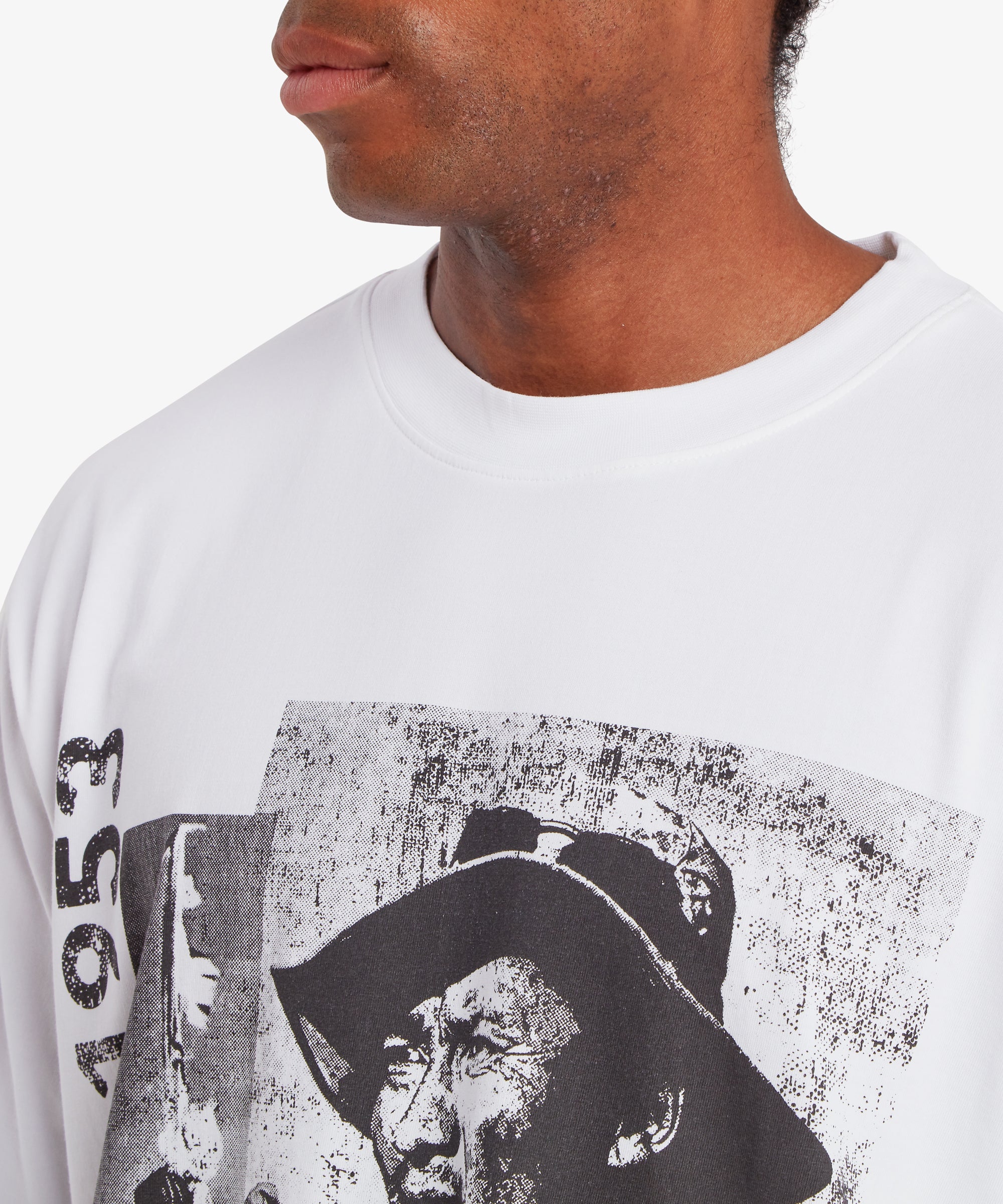 A close up of a man wearing a relaxed fit, white T-shirt. The collar and the top of the T-shirt are visible. A graphic can be seen on the front of the T-shirt  depicting Tenzing Sherpa and the number "1953" written vertically down the left side.