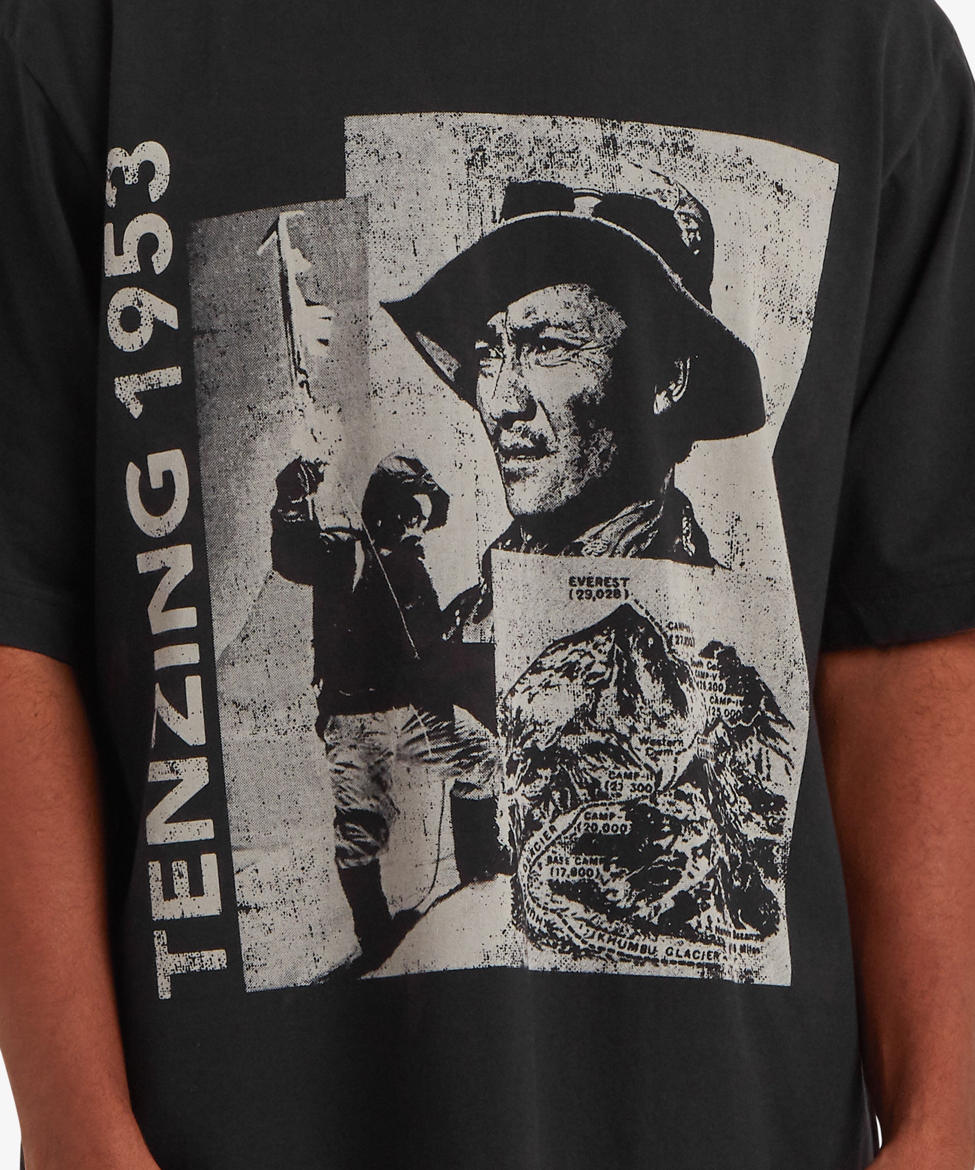 Close‑up of the graphic print on a black Tenzing 1953 T‑shirt, featuring mountaineering‑inspired illustrations and distressed textures that add a vintage expedition aesthetic.