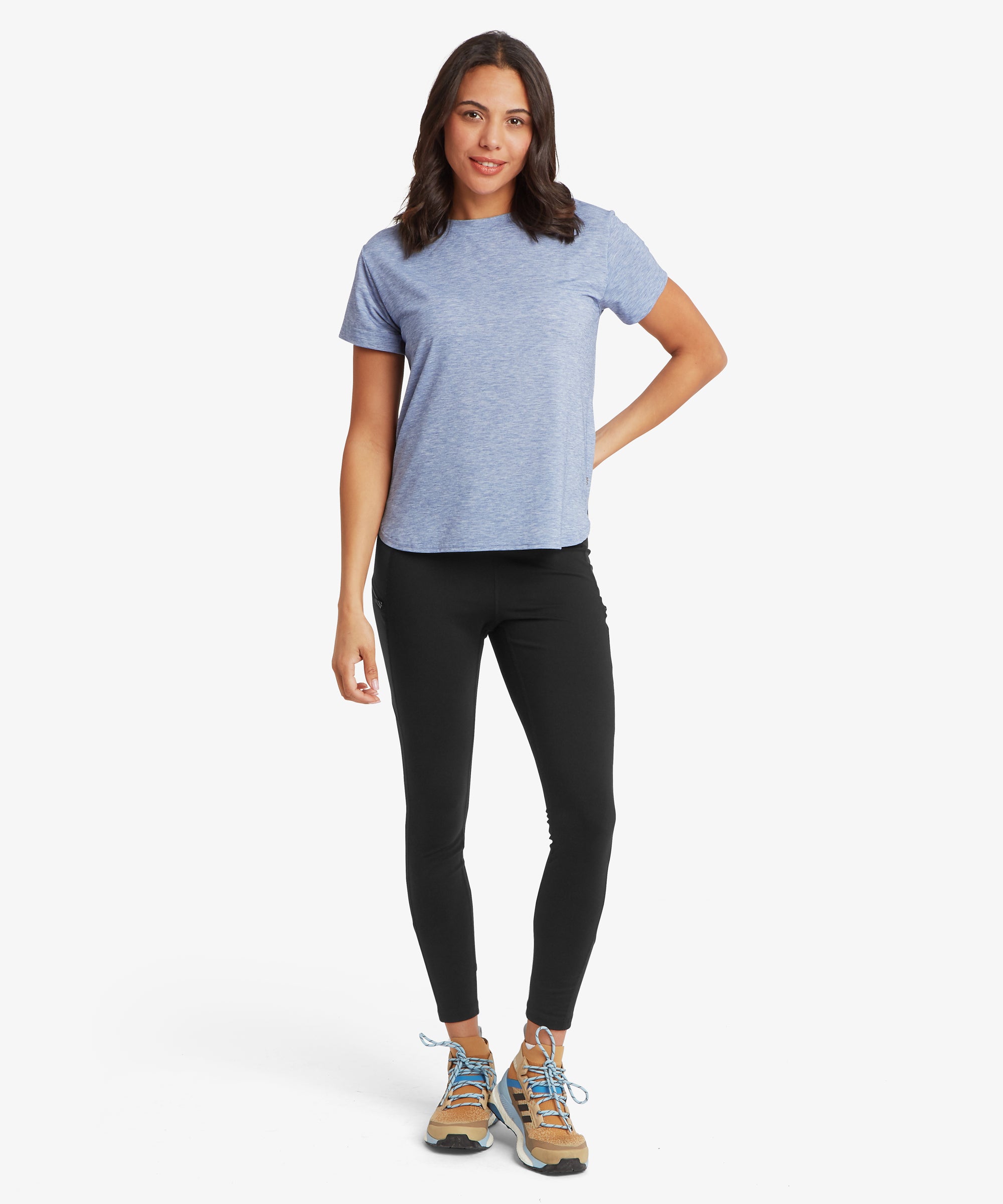 Front view of a person wearing a long‑sleeve crew‑neck top in a blue patterned fabric, paired with black leggings. The person is standing with arms relaxed at the sides.