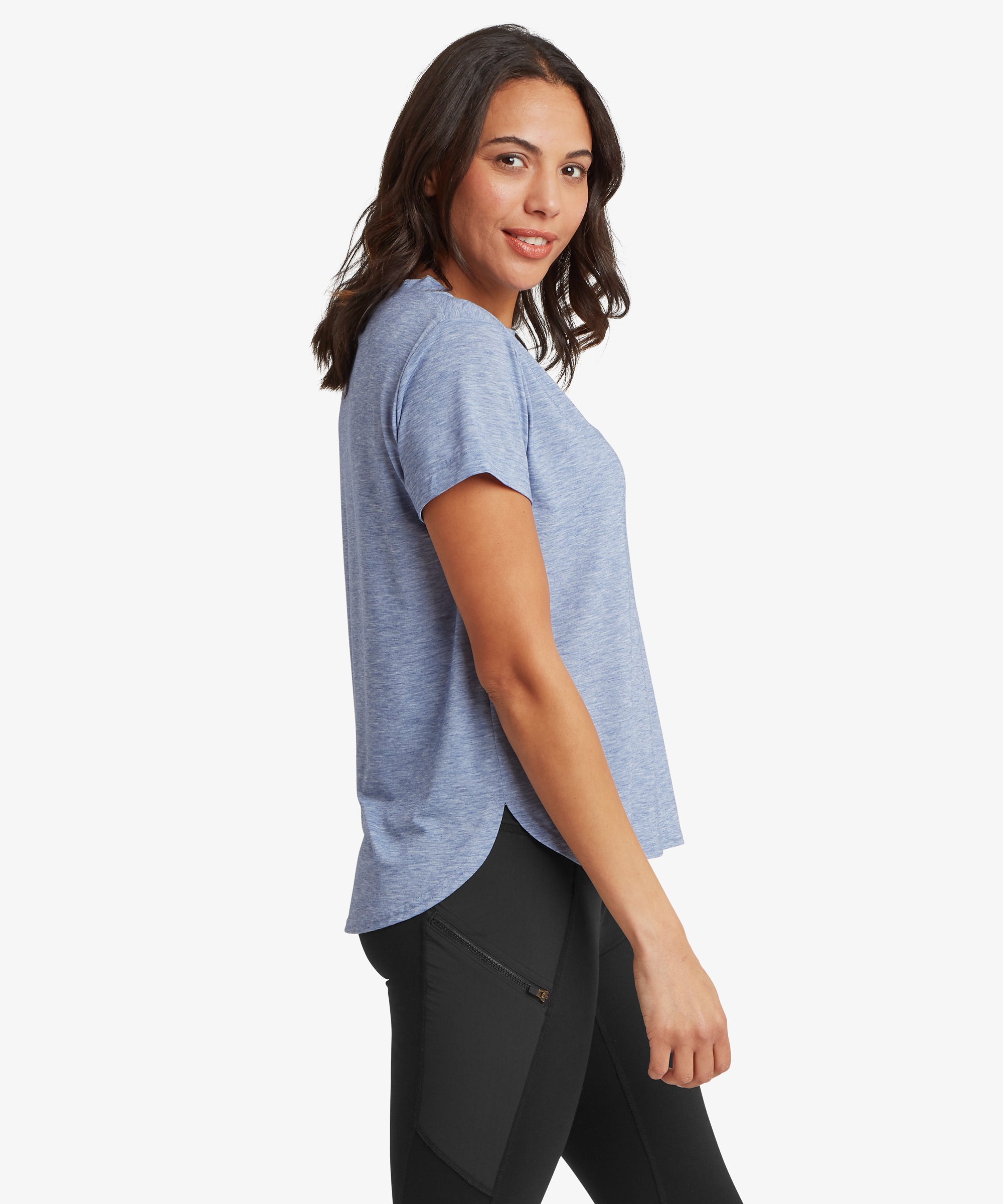 Side view of a blue patterned long‑sleeve crew‑neck top worn with black leggings. The person’s body is turned slightly to the side, showing the fit and length of the top.