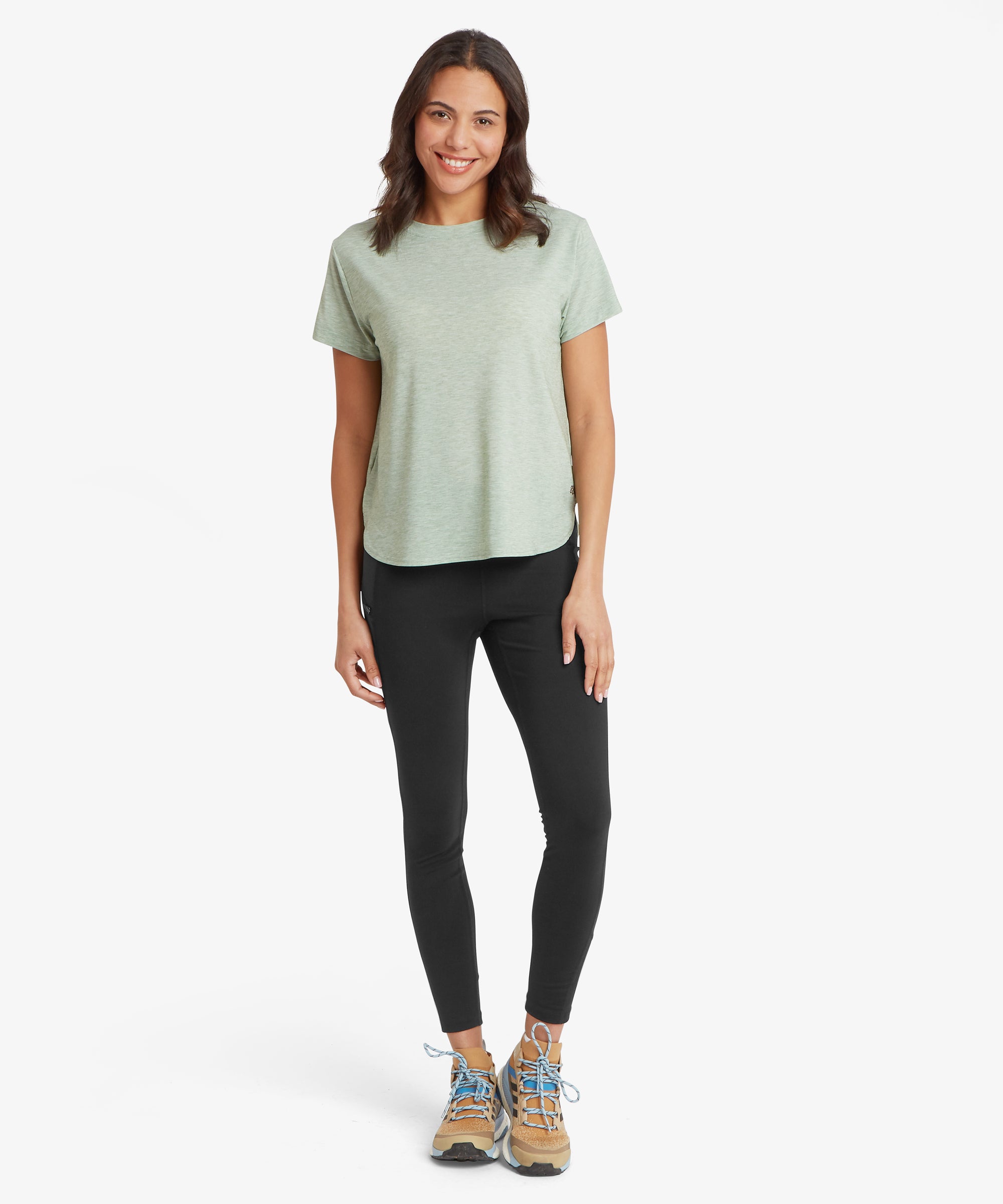 Front view of a person wearing a green patterned long‑sleeve crew‑neck top paired with black leggings. The image shows the overall fit of the top, including the neckline, sleeves, and hem.
