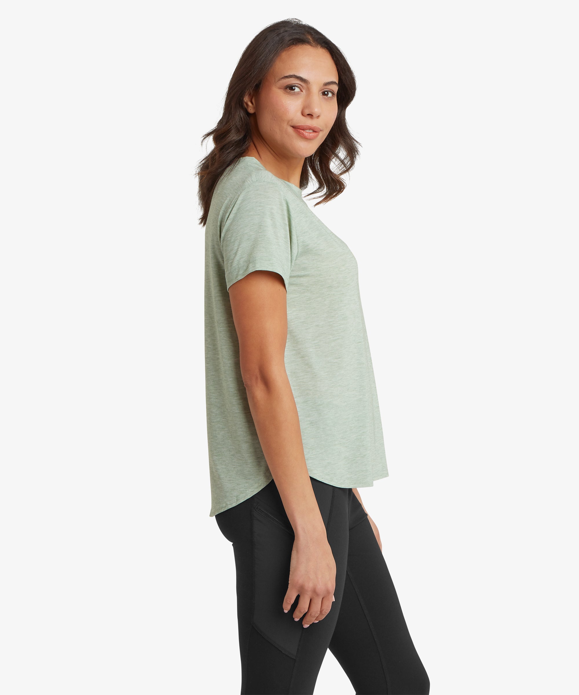 Side view of a green patterned crew‑neck top worn with black leggings. The photo highlights the side profile, sleeve length, and fit through the torso.