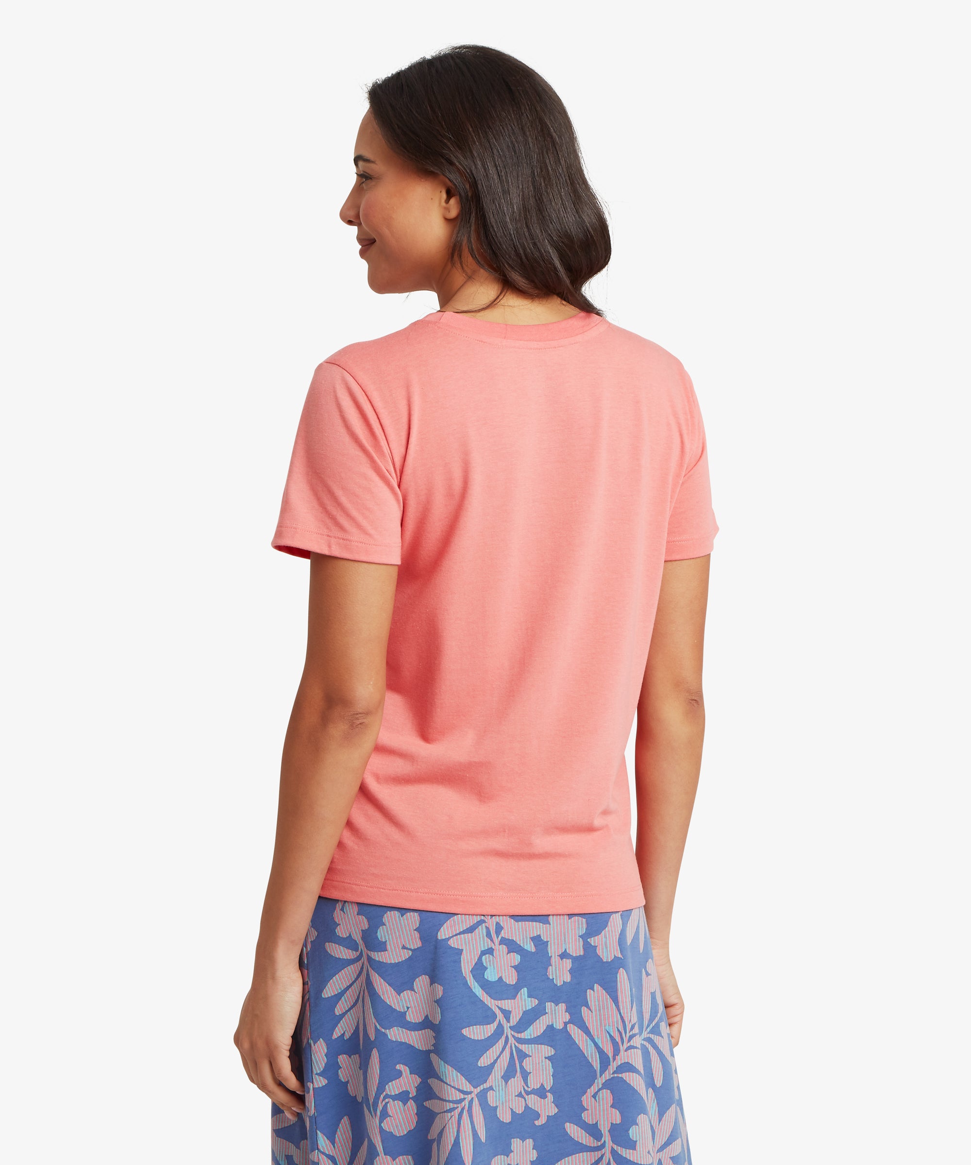Woman wearing a pink t-shirt and blue floral skirt on a white background