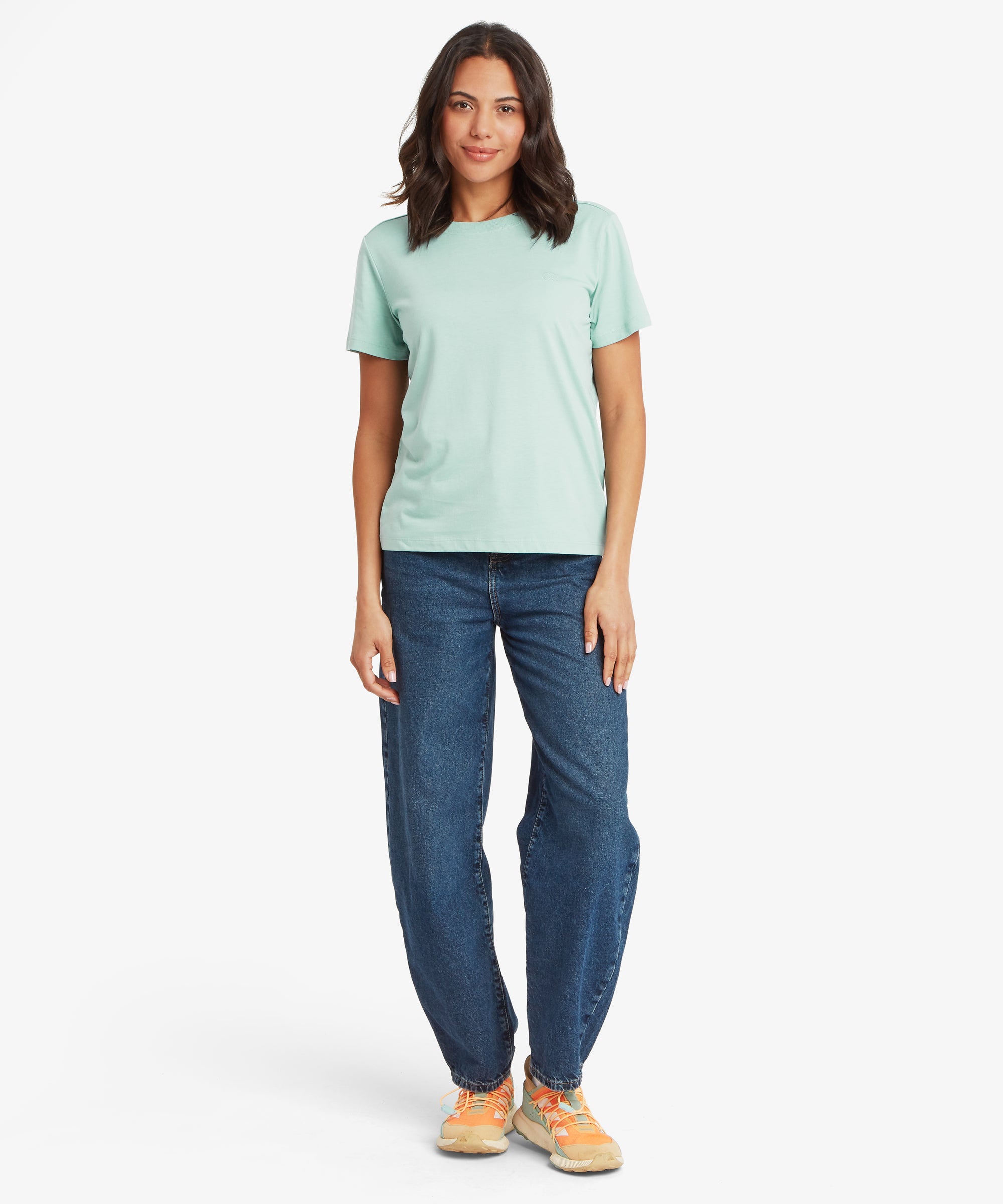Woman wearing a light green t-shirt and blue jeans on a white background