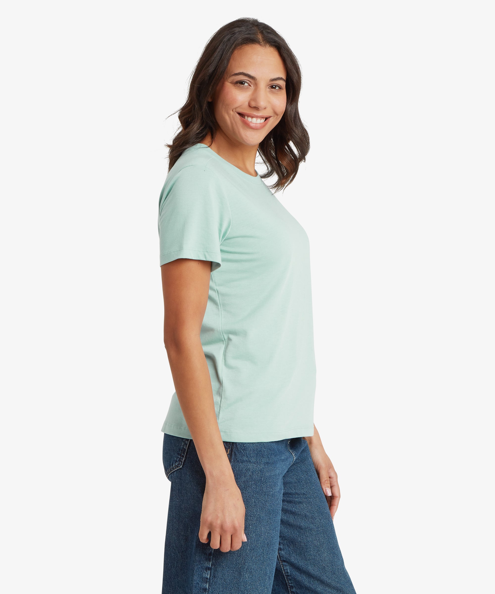 Side view of a mint green short‑sleeve crew‑neck tee paired with dark blue denim jeans, showing the relaxed fit, smooth lightweight jersey fabric, and clean side seam. One arm rests naturally by the side, highlighting the simple, casual warm‑weather styling ideal for everyday wear, travel, and laid‑back weekend outfits