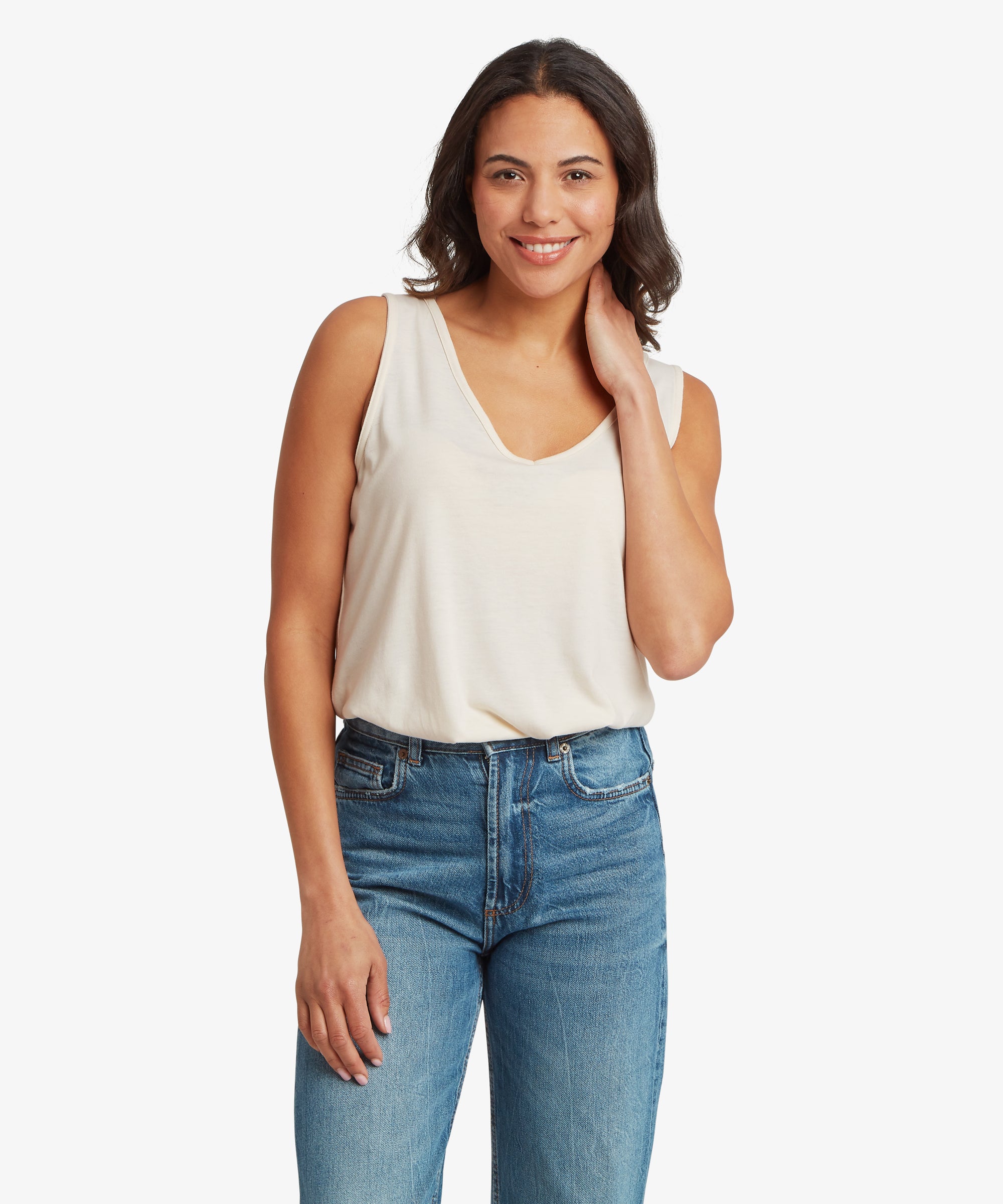 Three‑quarter front view of a cream women’s V‑neck tank top worn with mid‑wash denim jeans. The image highlights the tank’s soft drape, relaxed fit, and wide‑strap V‑neck design suitable for warm‑weather casual wear.