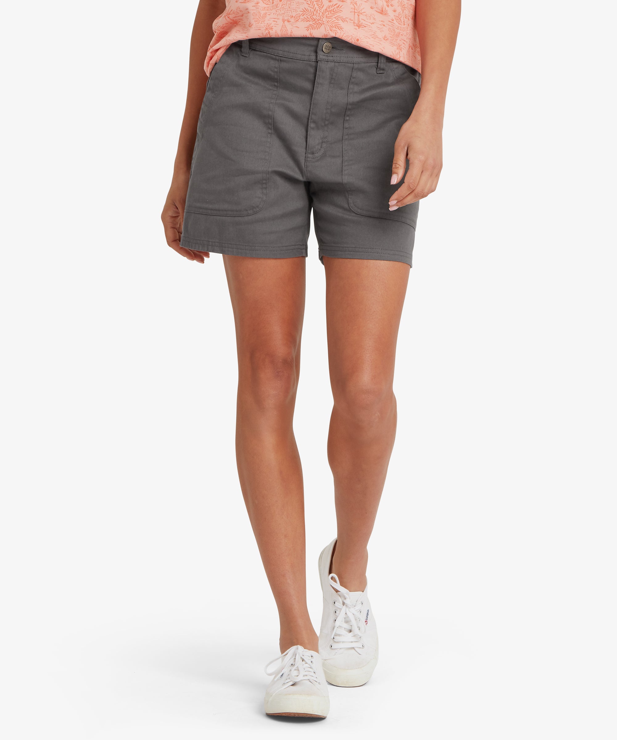 Front view of charcoal grey mid‑thigh shorts with a peach patterned sleeveless top tucked lightly at the waist. The shorts feature angled pockets, a clean front closure, belt loops, and soft structured woven fabric. White canvas trainers complete the outfit, highlighting a practical, casual look suitable for warm‑weather walking, sightseeing, and everyday comfort.
