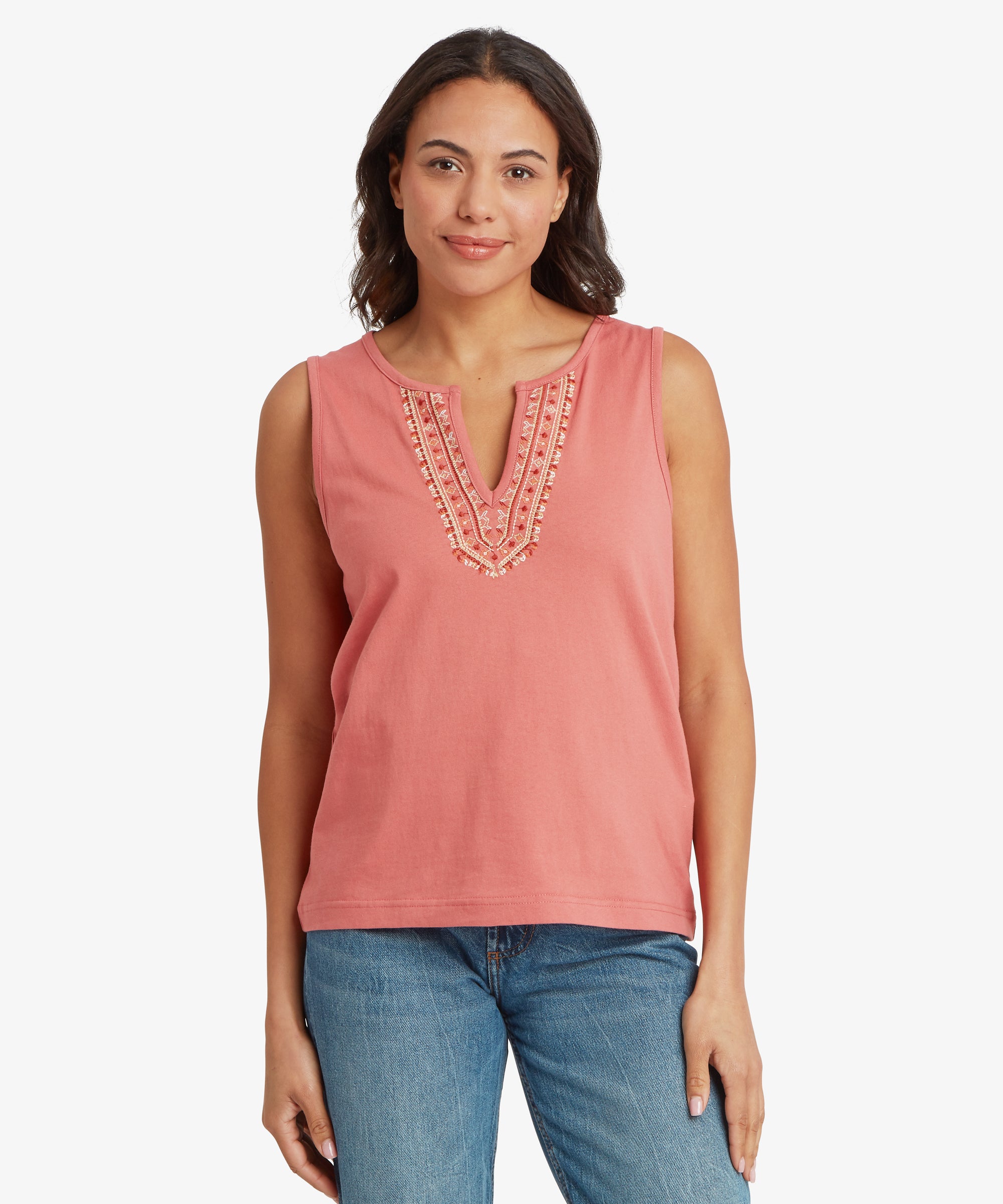 Front view of a soft rose‑pink sleeveless top featuring a decorative split‑neck opening with intricate embroidered detailing in a tonal thread pattern. The top has a relaxed drape and sits comfortably over mid‑wash blue denim jeans. Both arms rest naturally by the sides.