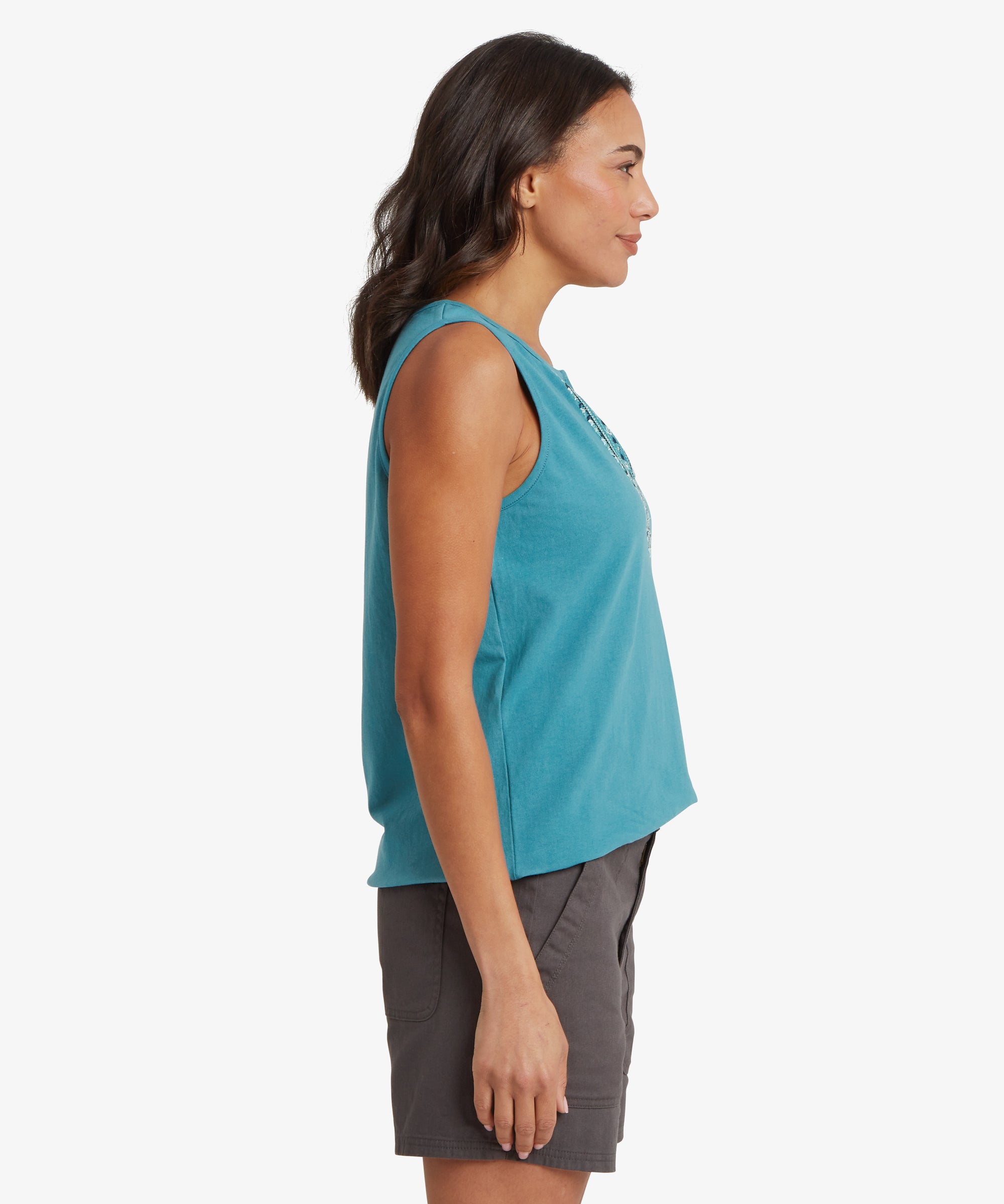 Side view of a turquoise sleeveless top paired with charcoal grey mid‑thigh shorts. The top has a relaxed drape with a smooth knit texture and a decorative embroidered detail visible along the neckline edge. The shorts feature angled pockets, reinforced stitching, and a soft woven fabric designed for comfort and movement.