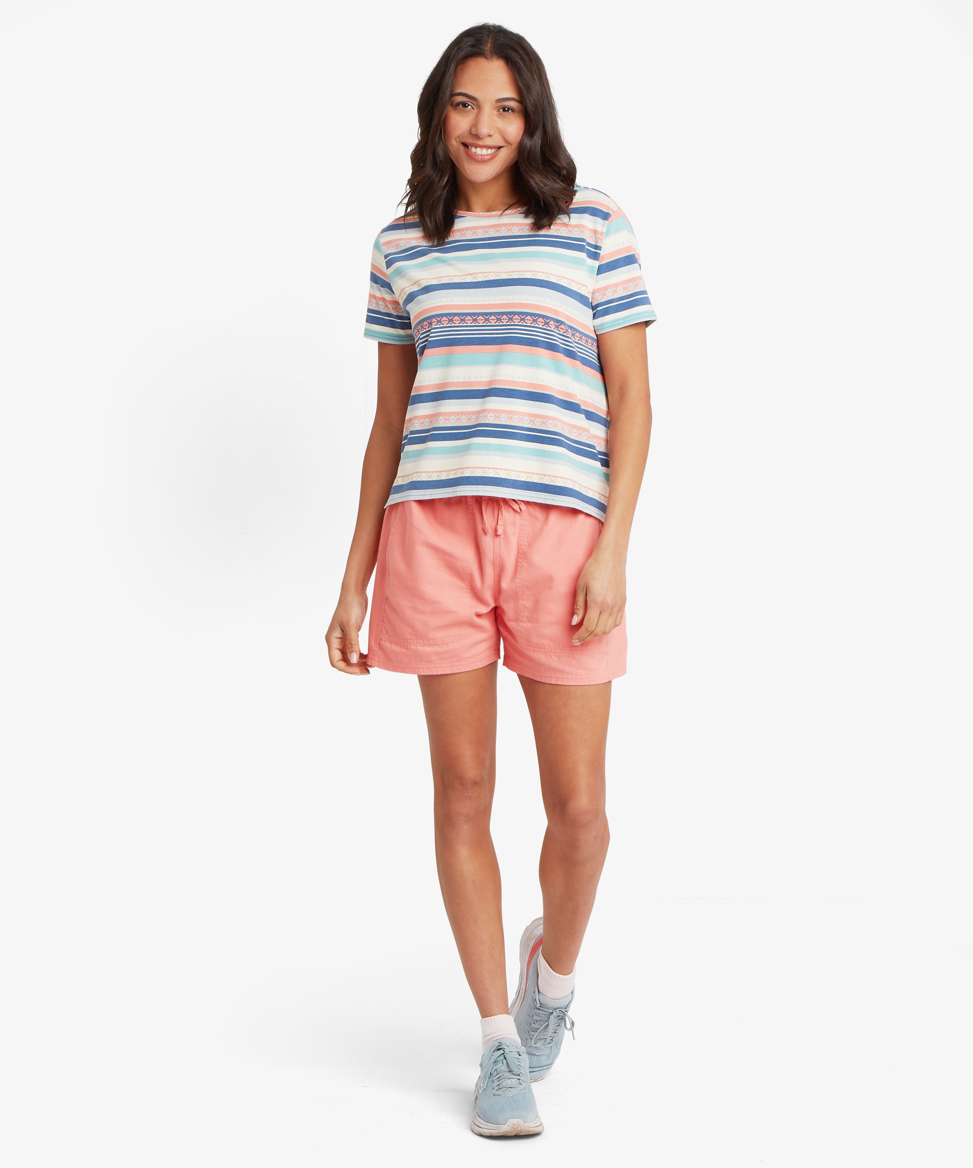 Eine vollstŠndige Vorderansicht eines locker sitzenden, mehrfarbig gestreiften T-Shirts, kombiniert mit lockeren korallenroten Shorts mit Kordelzug. Die weichen Pastellstreifen und das dekorative horizontale orangefarbene Motiv des T-Shirts sind deutlich zu sehen.