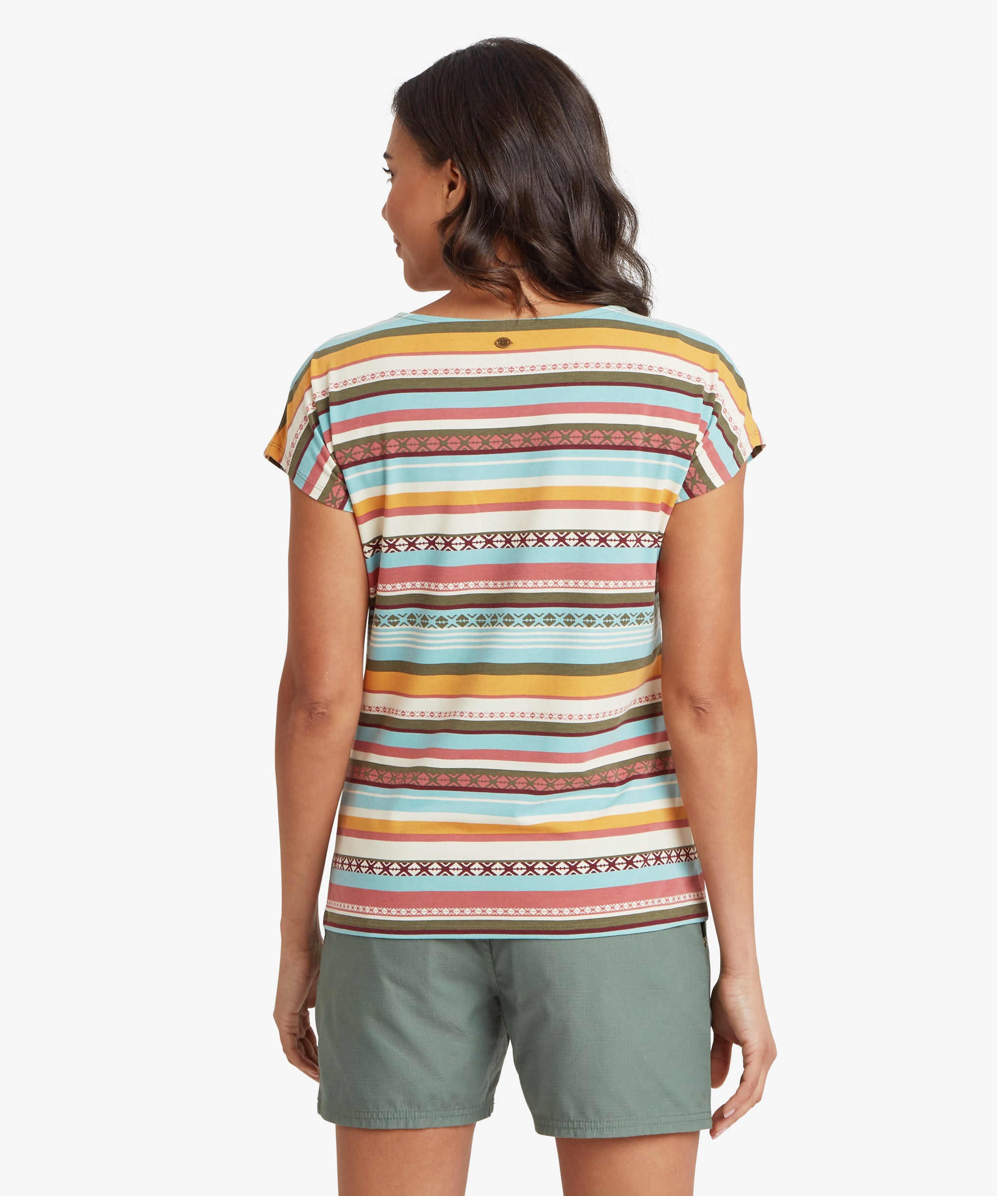 Back view of a woman wearing a multicolour striped T-shirt with horizontal stripe alignment across the shoulders and back. The shirt falls loosely over green shorts and has a straight hem that sits at the hip.