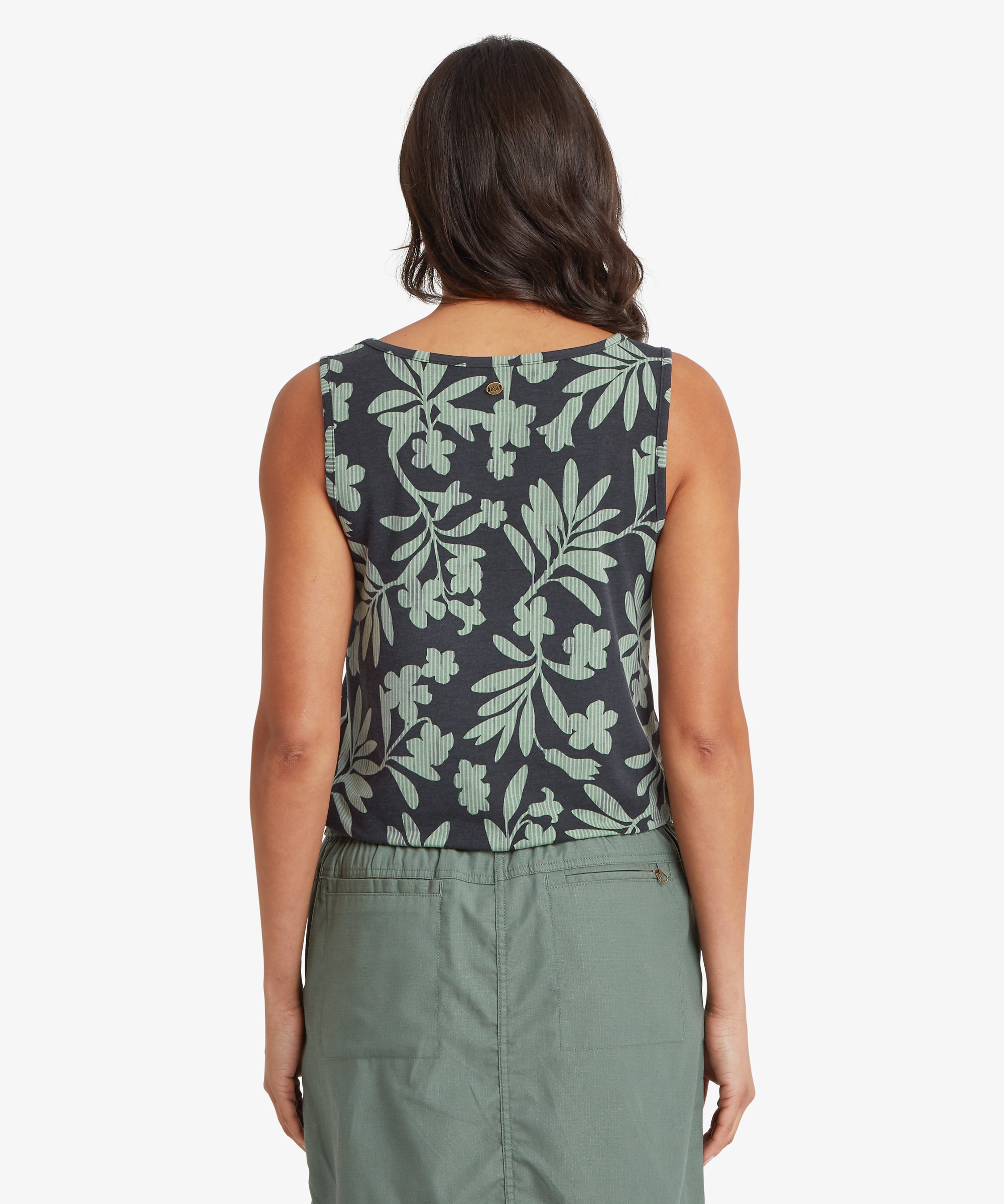 Back view of a woman wearing a sleeveless green printed top with a straight back hem and relaxed fit, paired with a green skirt. Her shoulders are relaxed and her hair falls just above the neckline.