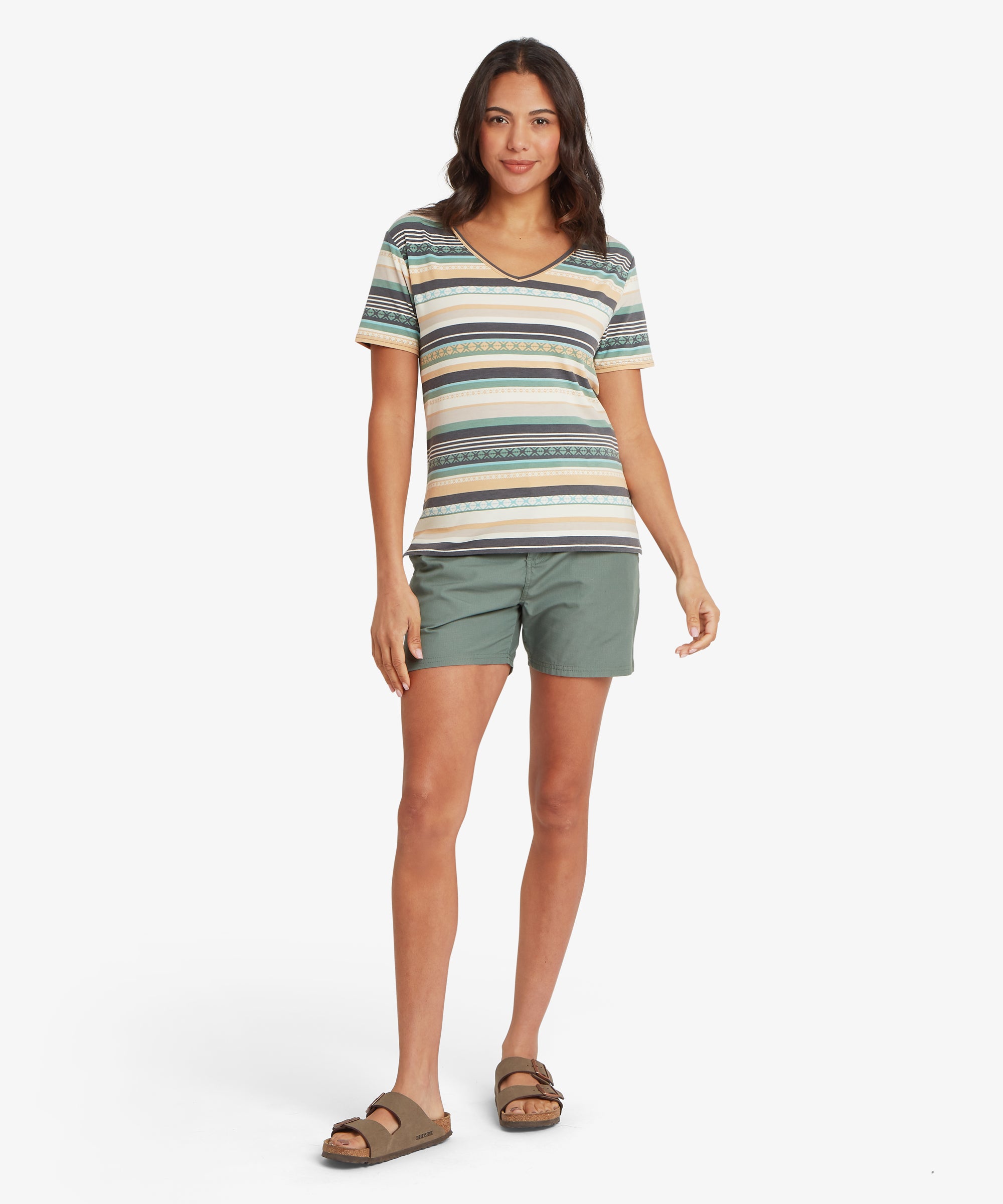 Woman standing upright wearing a striped short-sleeve V-neck T-shirt tucked loosely over olive green shorts and flat sandals, showing the hip-length hem, casual fit, and lightweight fabric.