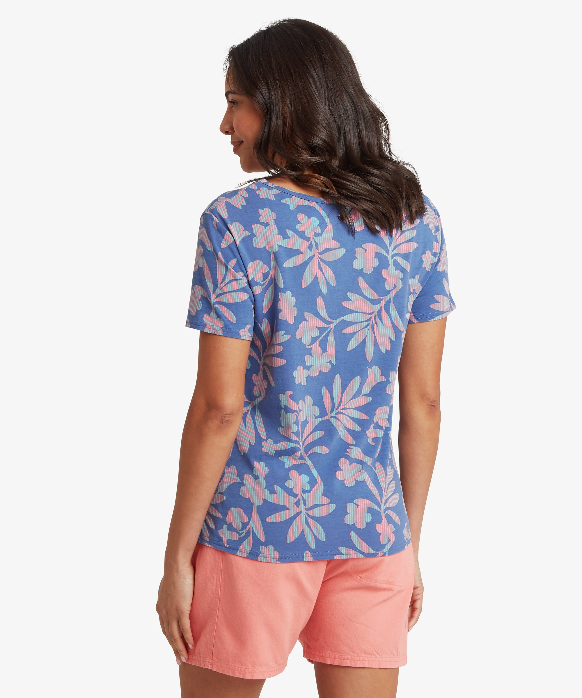 Back view of a woman wearing a blue floral short-sleeve T-shirt paired with coral shorts, showing the smooth back panel, straight hemline, and relaxed fit across the shoulders.