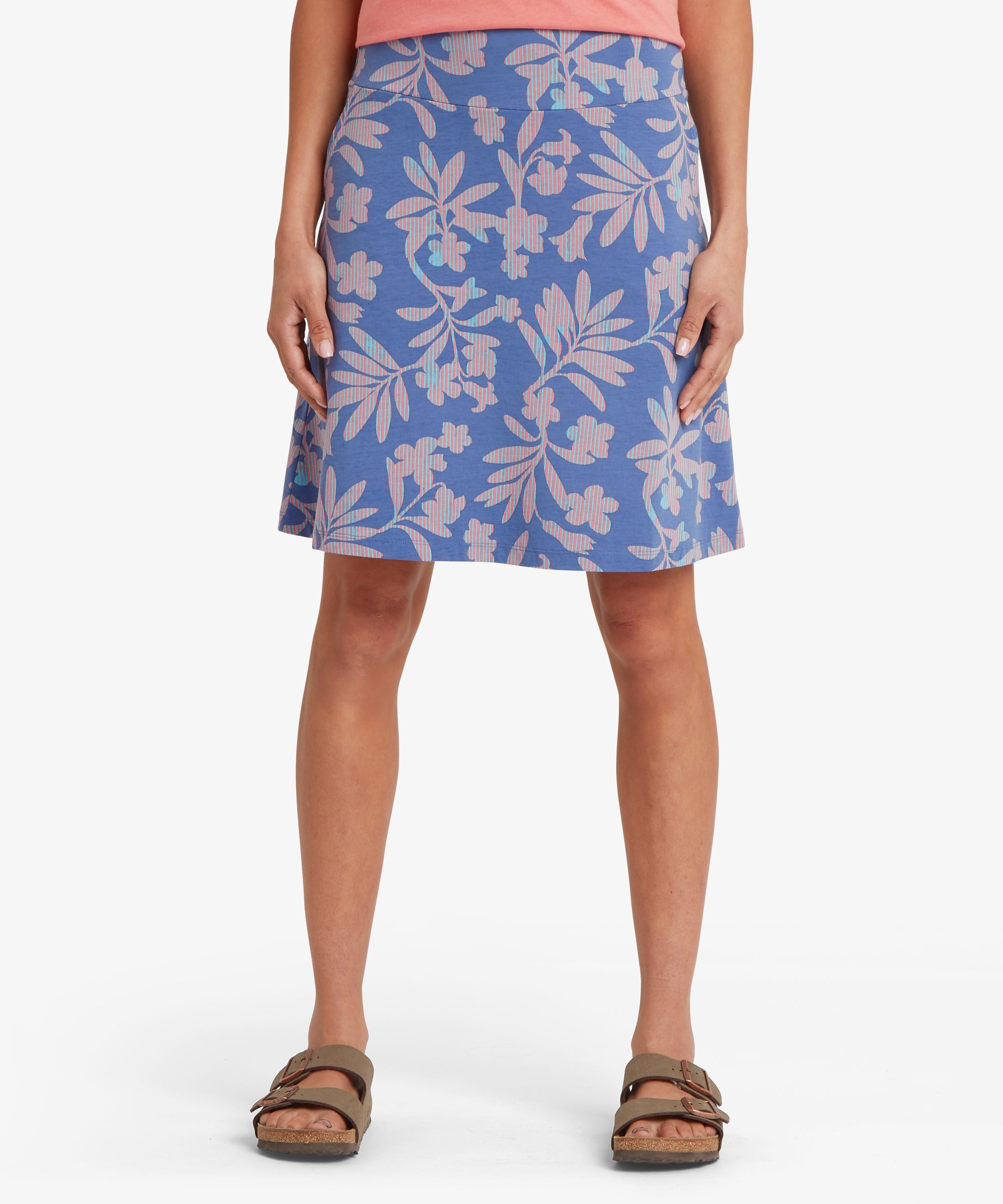 Front view of a woman wearing a blue knee-length skirt with a relaxed A-line fit, smooth waistband, and pink floral print, styled with sandals.