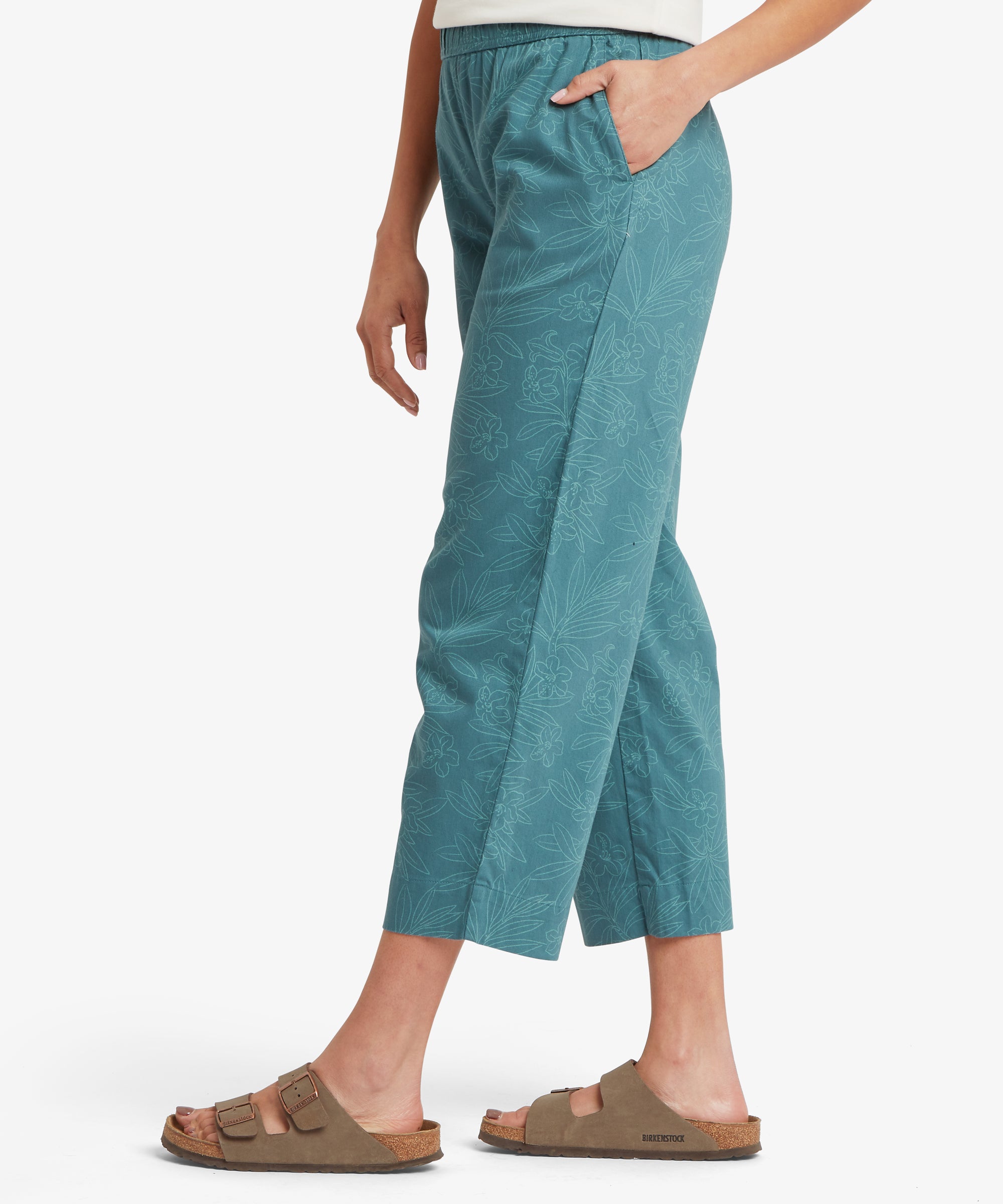 Side view of a woman wearing teal cropped trousers showing a straight-leg silhouette, mid-rise waist, and relaxed fit through the hip and thigh.