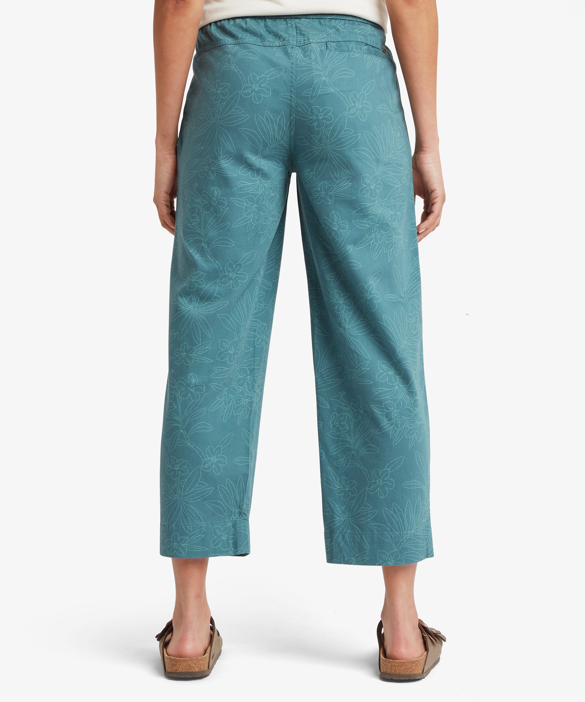 Back view of a woman wearing teal cropped trousers with a straight leg, elastic waistband, and relaxed fit, falling just above the ankles.