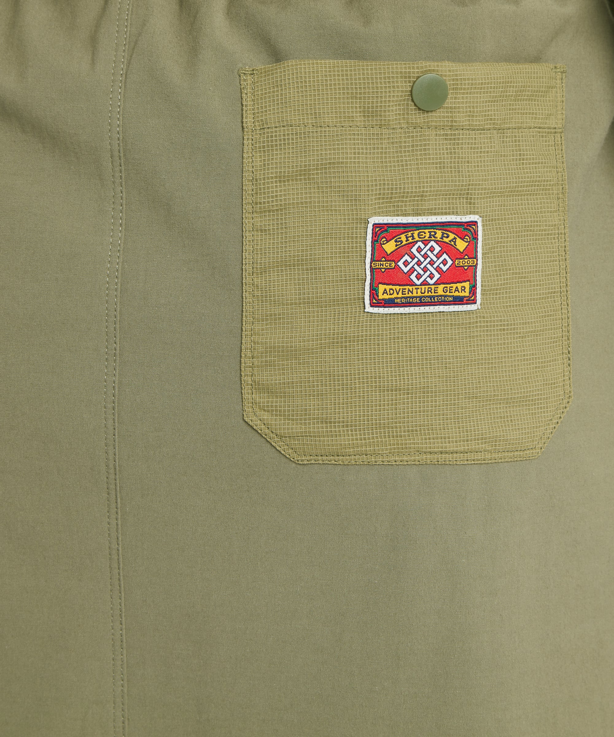 Close-up of a green skort pocket with a Sherpa Adventure Gear mountaineering patch stitched to the centre.
