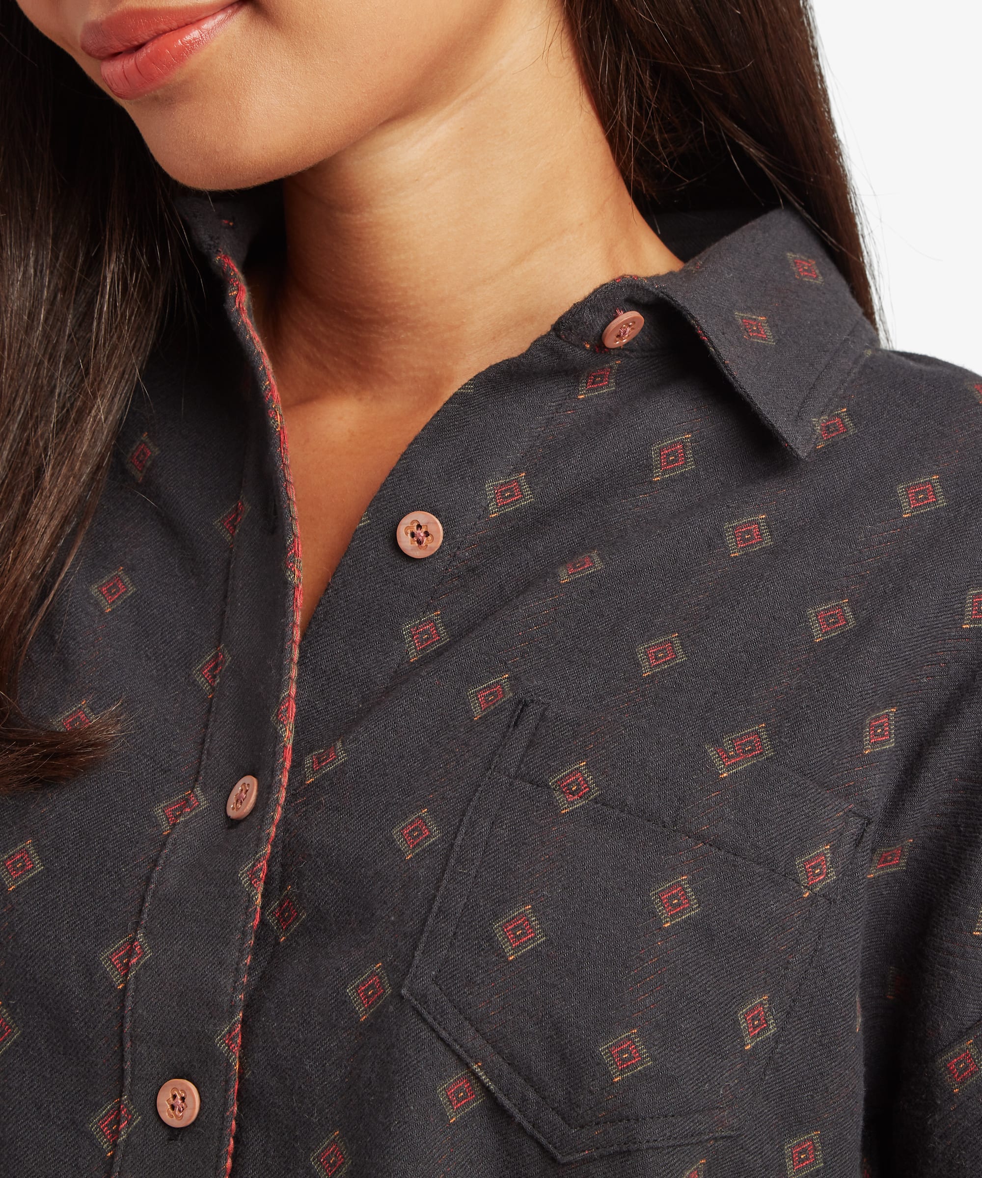 Close-up of a woman wearing a black printed button-up shirt featuring a pointed collar, button-front placket, and geometric motif pattern.