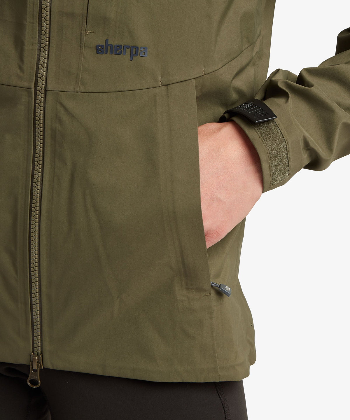 A female model wearing the Sherpa Adventure Gear Beyul 3L Jacket in green.