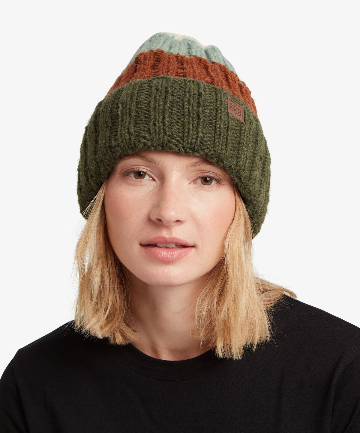 A woman with blonde hair wearing a chunky knit beanie hat with horizontal stripes of sage green.