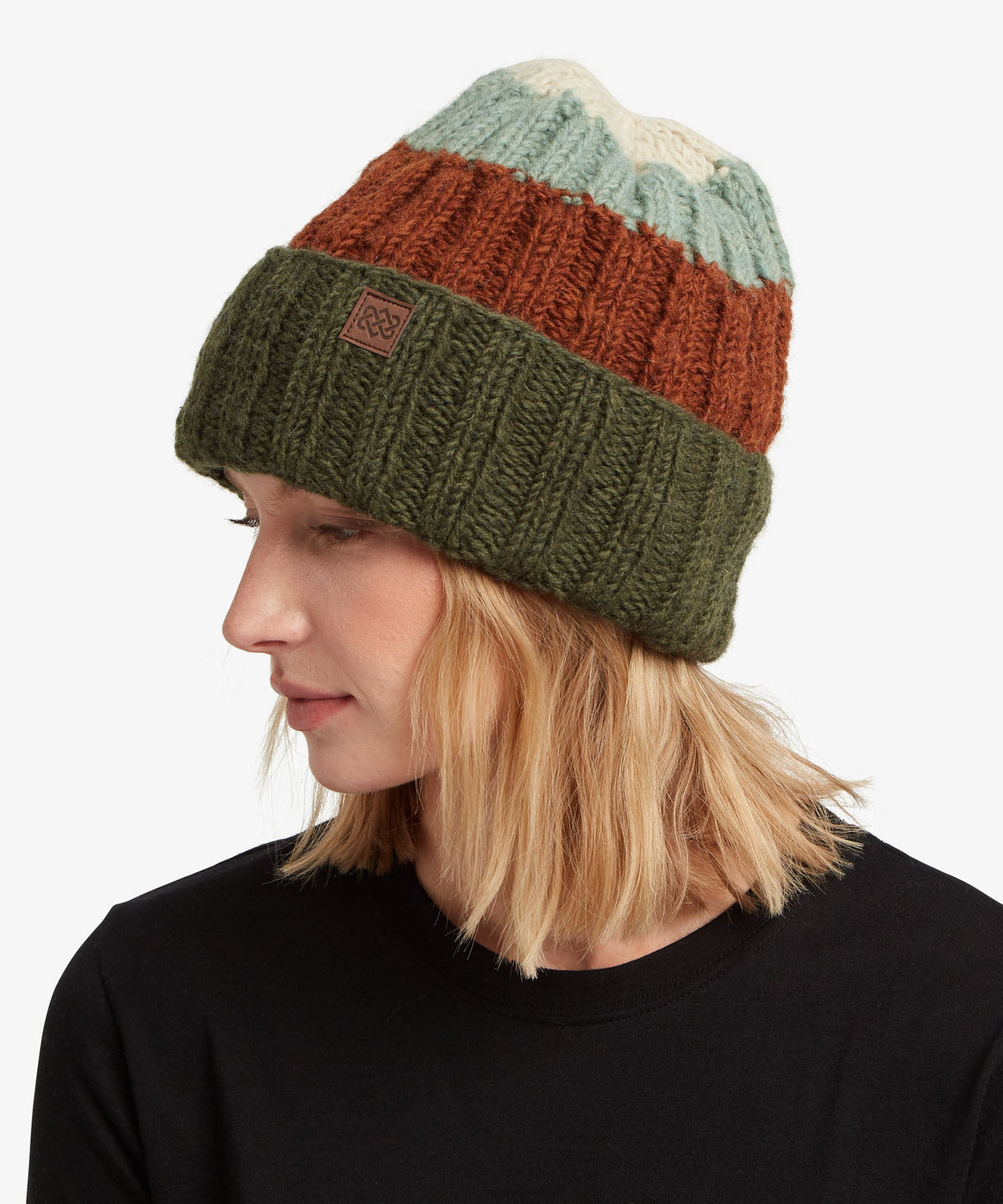 A woman in profile wearing a multi-colored knit beanie with green, rust orange.