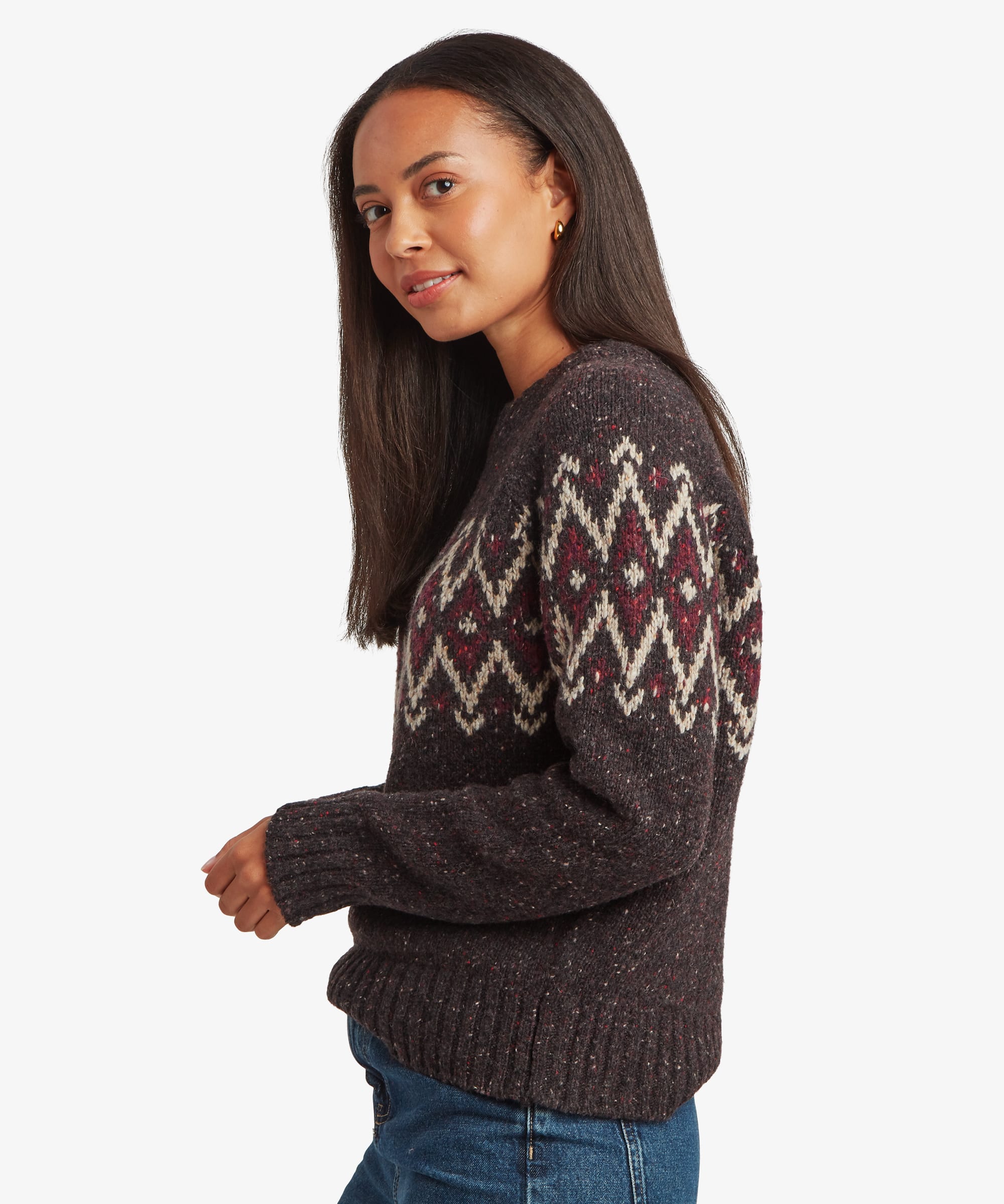 Woman wearing a black Fair Isle sweater in side profile. The image highlights the sweater’s soft knit fabric, long sleeves, and patterned upper yoke extending around the garment.
