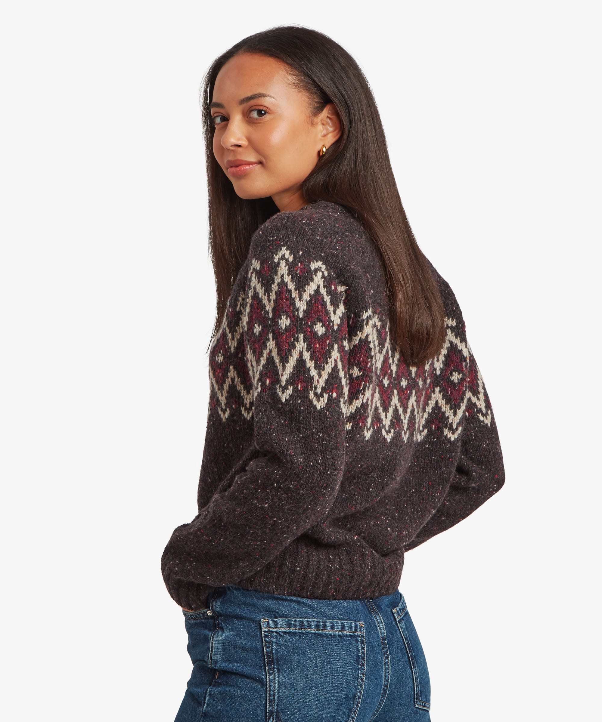 Rear three-quarter view of a woman wearing a charcoal-black Fair Isle sweater. The wraparound geometric pattern across the shoulders and upper back is clearly visible.