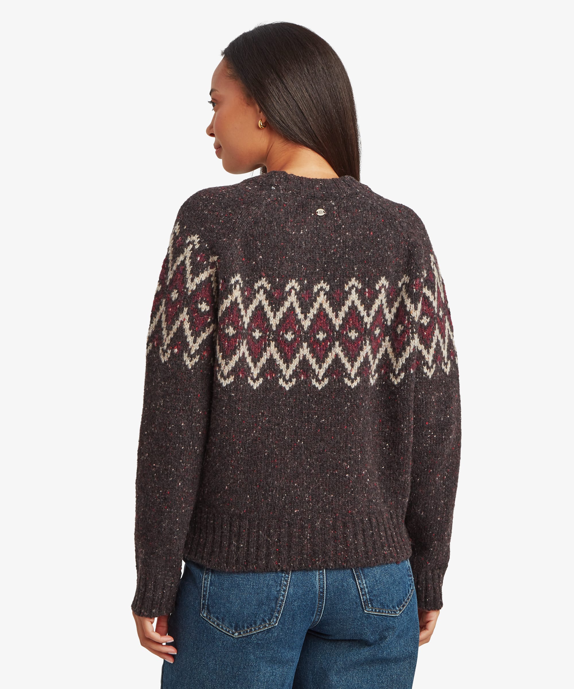 Back view of a woman wearing a dark knit Fair Isle sweater with burgundy and cream geometric detailing across the upper back. Features a crew neck, long sleeves, and relaxed fit.