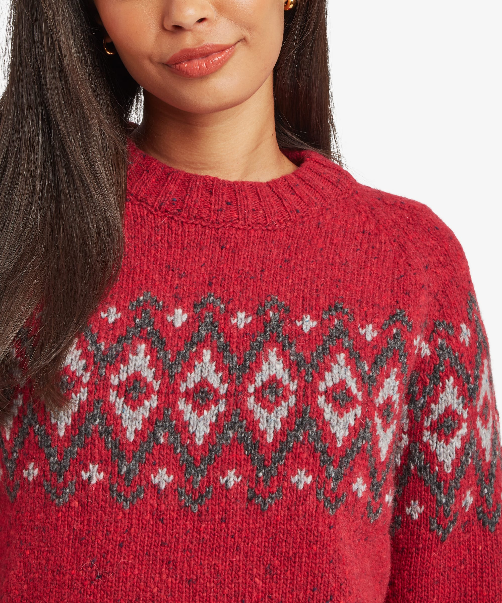 Close-up of a woman wearing a red Fair Isle sweater. The detailed geometric pattern, textured knit fabric, and crew neckline are prominently displayed.