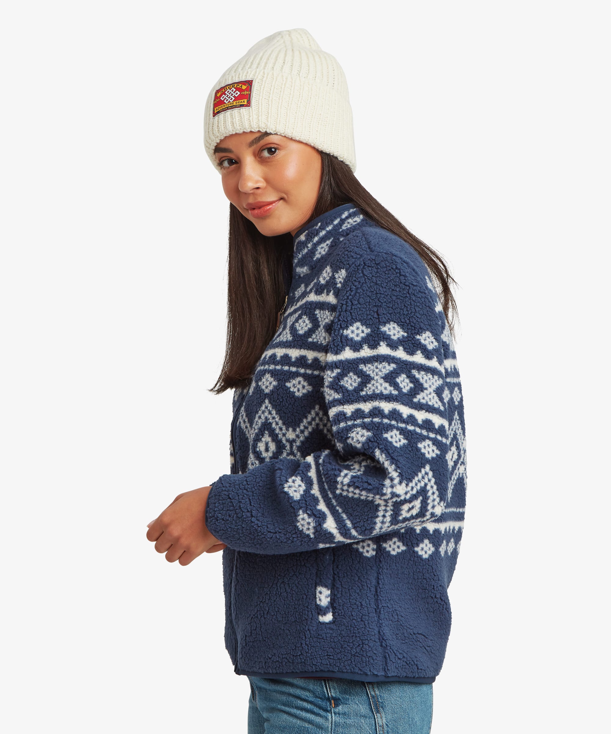 Side profile of a woman wearing a blue fleece zip jacket with white Fair Isle-inspired patterning. Highlights the stand collar, zip closure, and relaxed fit.