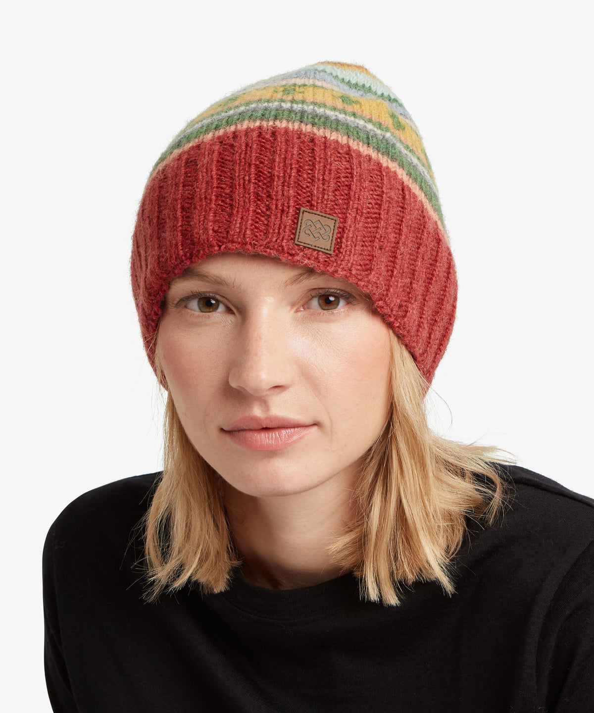 A woman wearing a ribbed knit beanie hat with horizontal stripes in red, yellow, green.