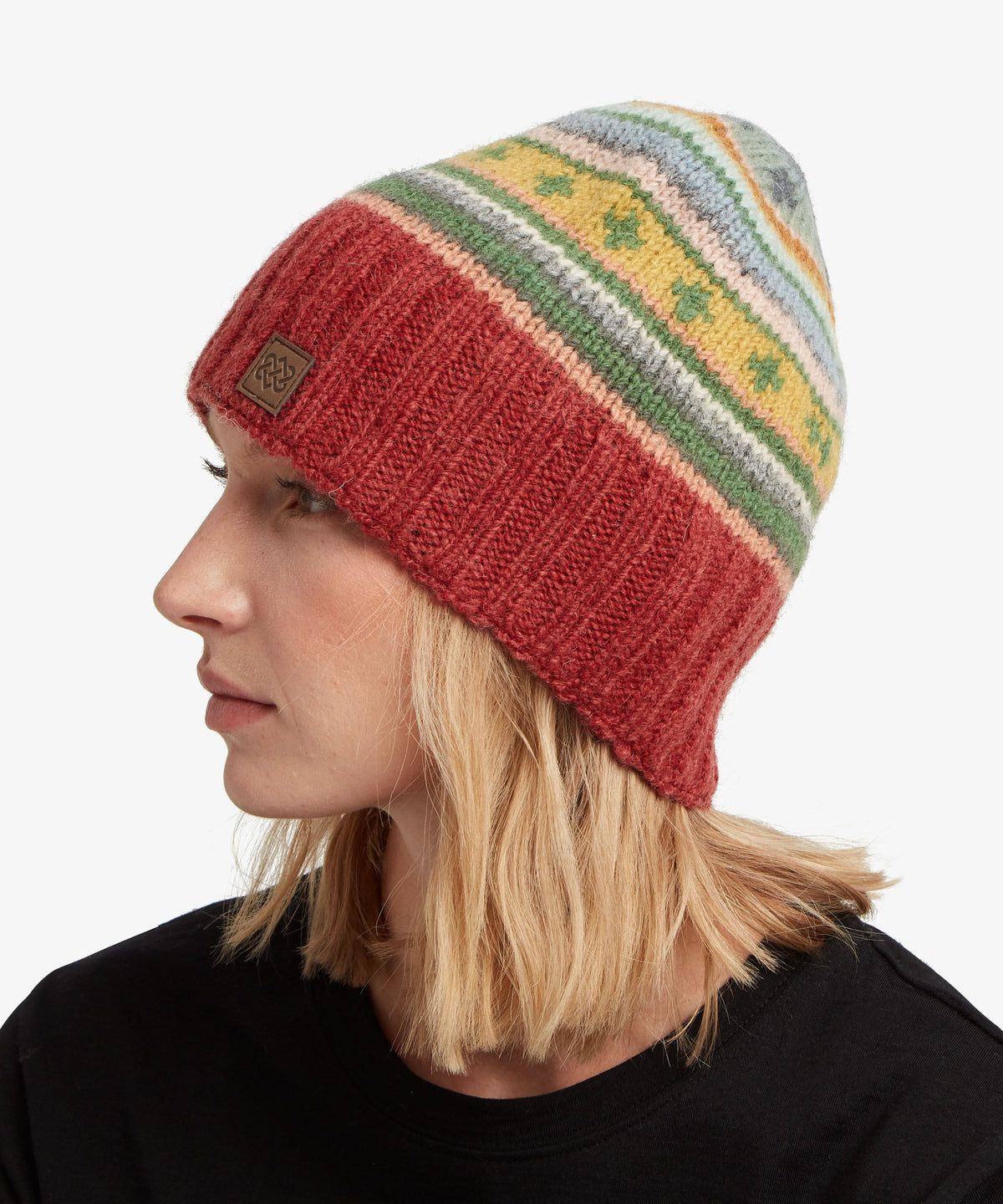 A woman in profile wearing a knit beanie hat with a solid rust-red lower half.