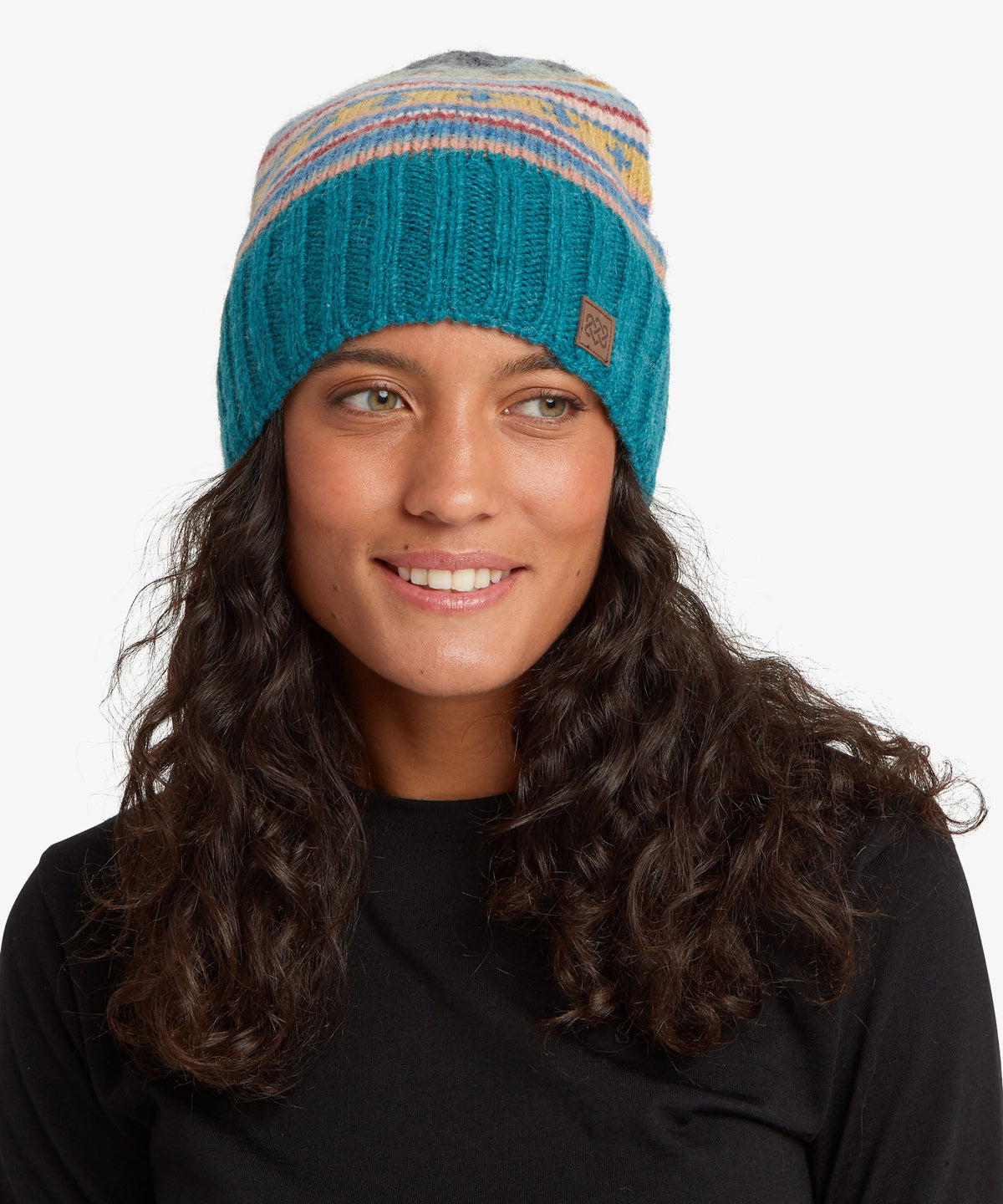 Woman with long, wavy dark brown hair in a teal blue knit beanie with a multicoloured striped band.