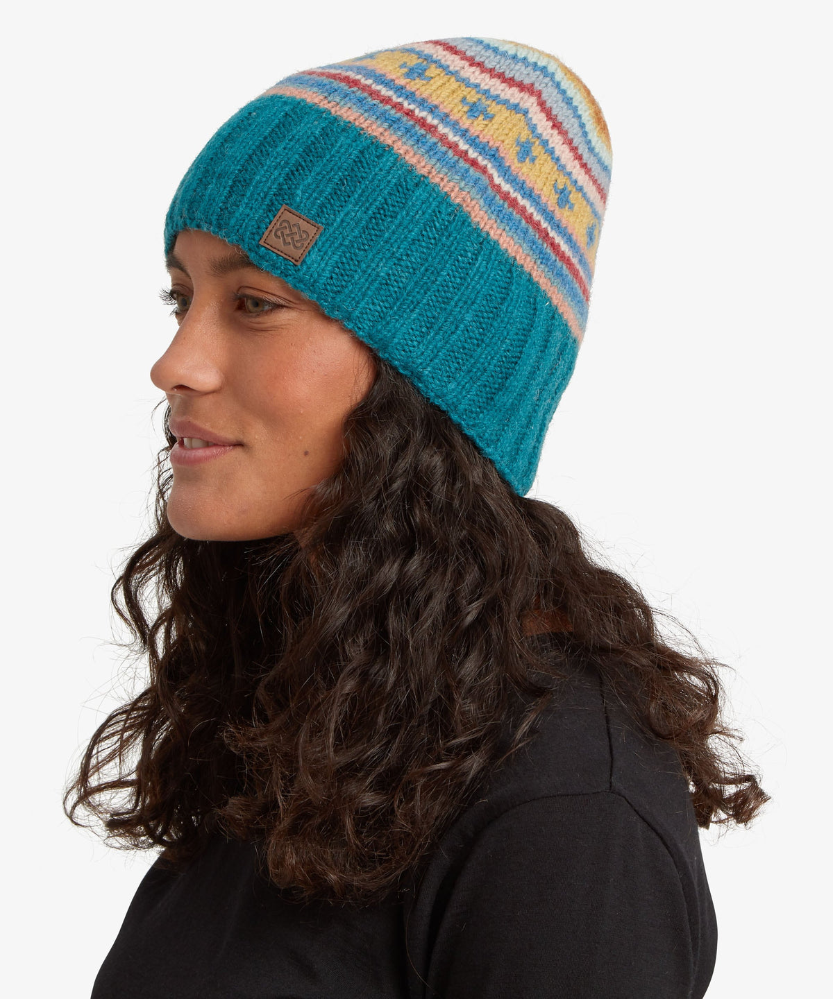 A woman in profile wearing a turquoise knit beanie with multicolored Fair Isle stripes.